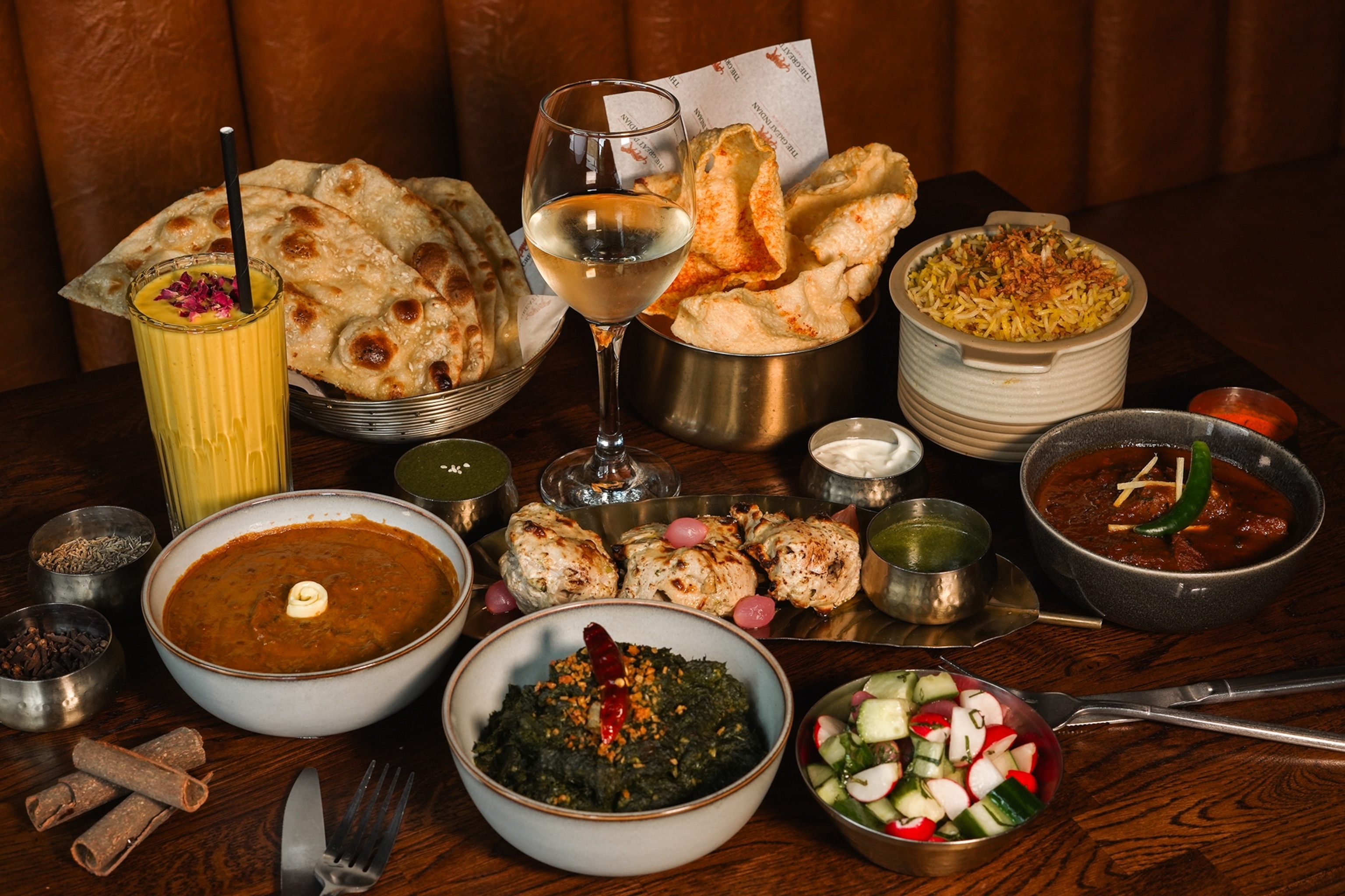 A selection of different Indian dishes, from curries to rice bowls, neatly arranged on a pub table.