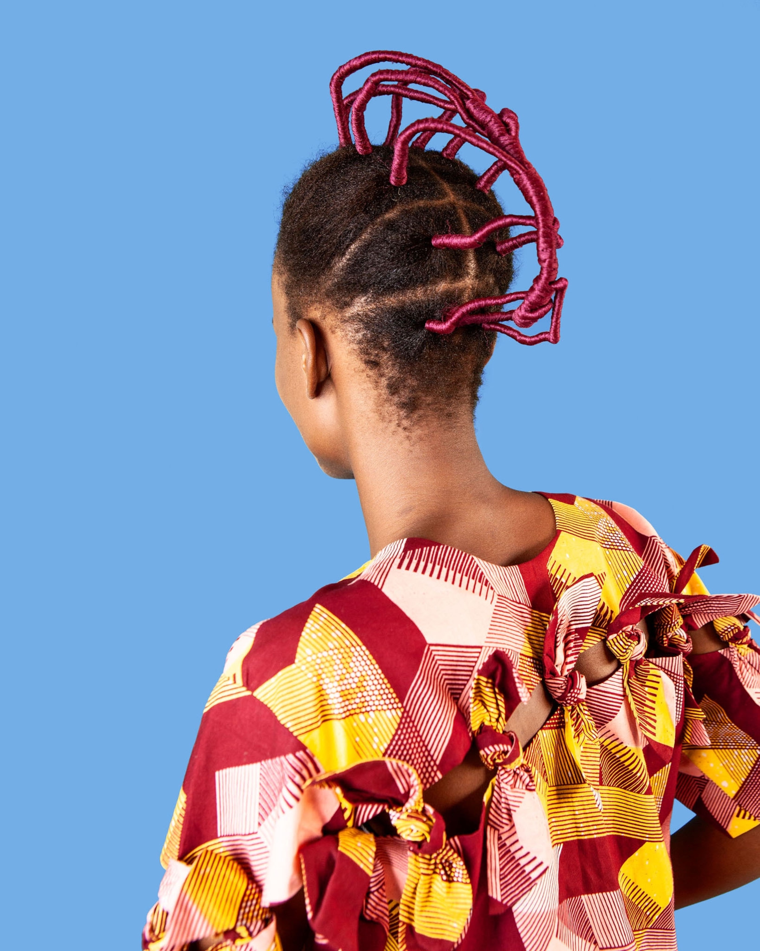Picture of woman with hair twisted with magenta thread.