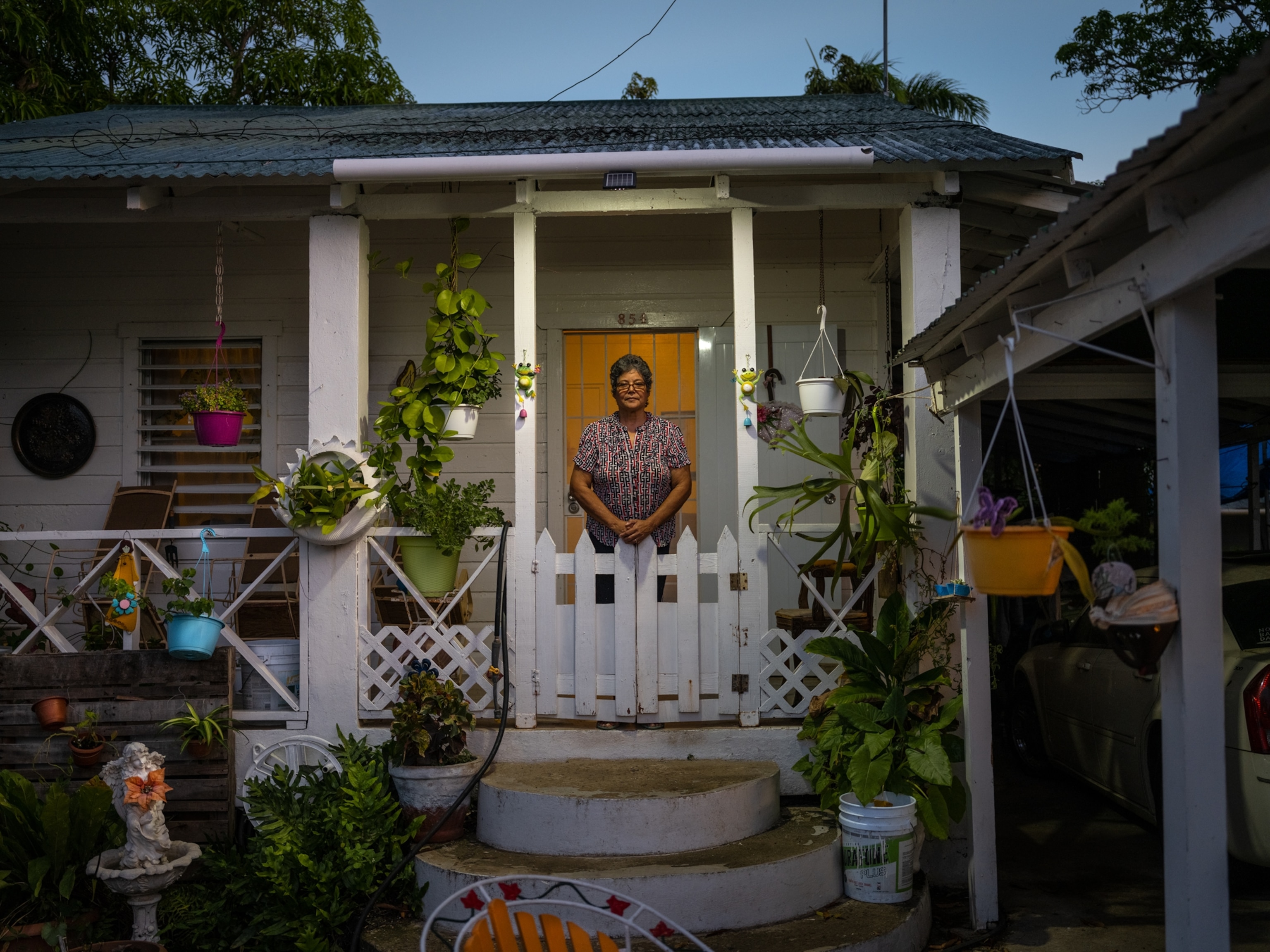 Woman at the front porch decorated with hanging flower baskets.