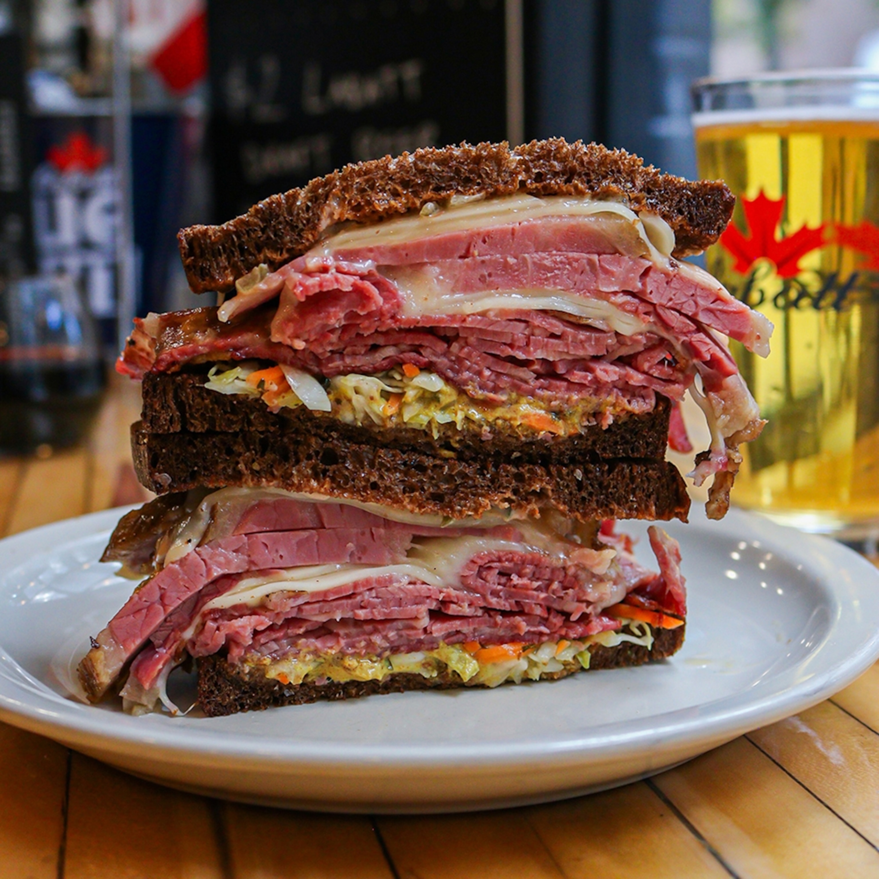 A stacked sandwich on a plate with pastrami, cheese and sauerkraut as a filling.