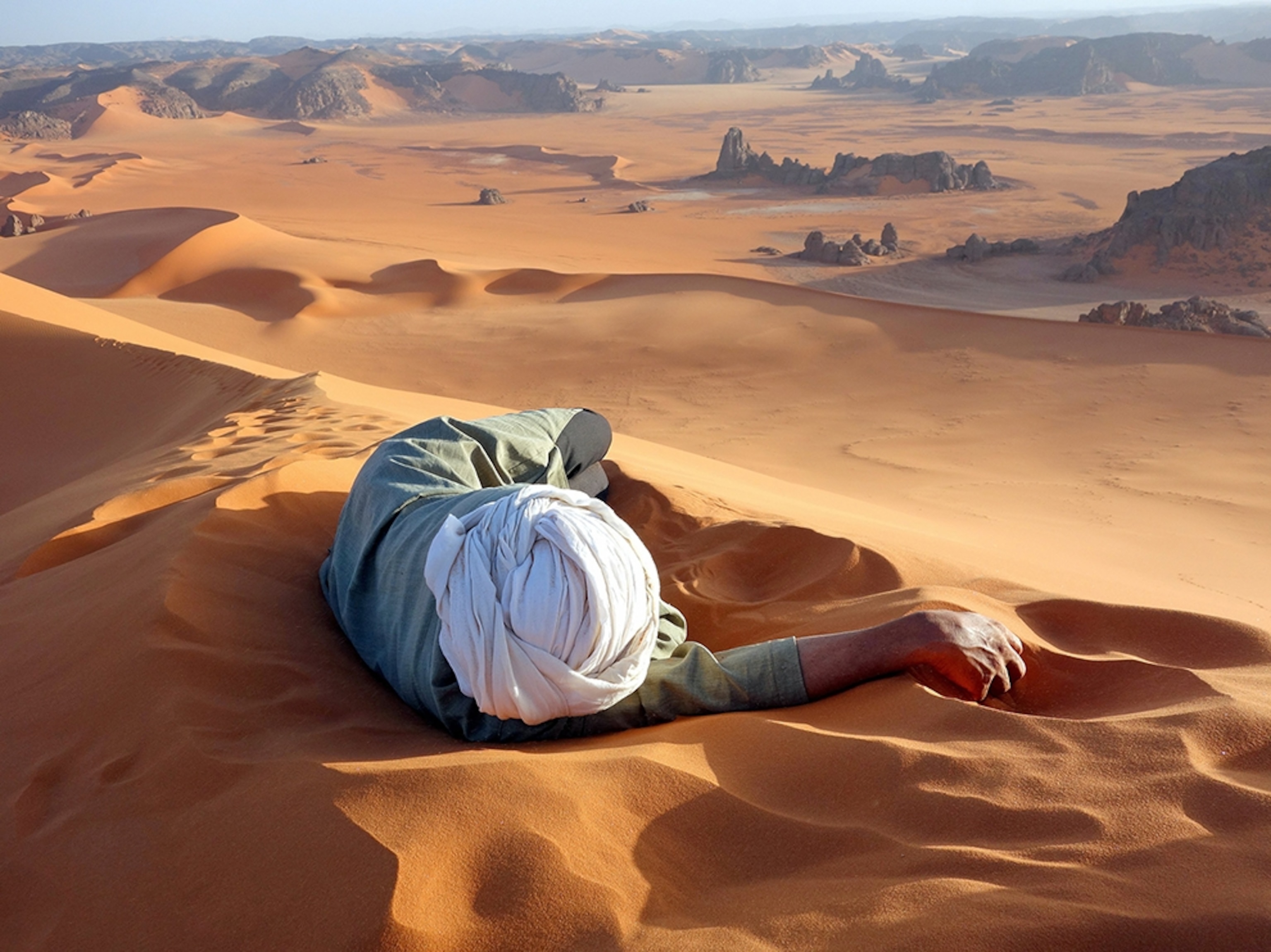 a man resting at the summit of Tin-Merzouga, Tassili N'Ajjer National Park