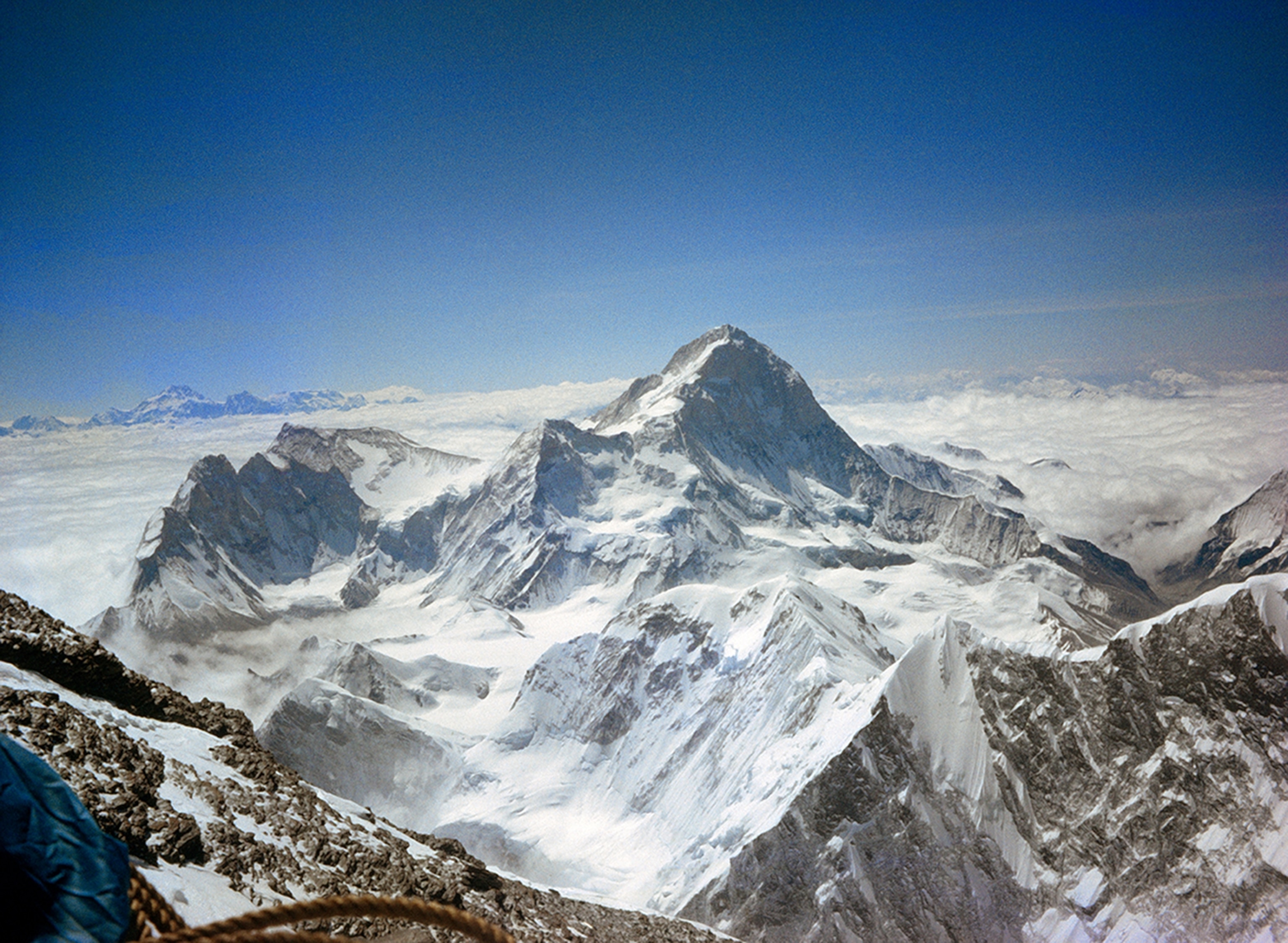 Makalu, flanked by its subsidiary, Makalu II, dominates the scene. At left, Tibet’s 25,640-foot Chomo Lonzo looks across to the Kanchenjunga Massif, which armors the border between Nepal and Sikkim. On the distant right, India’s hot, dry plains appear dimly beyond the clouds.
