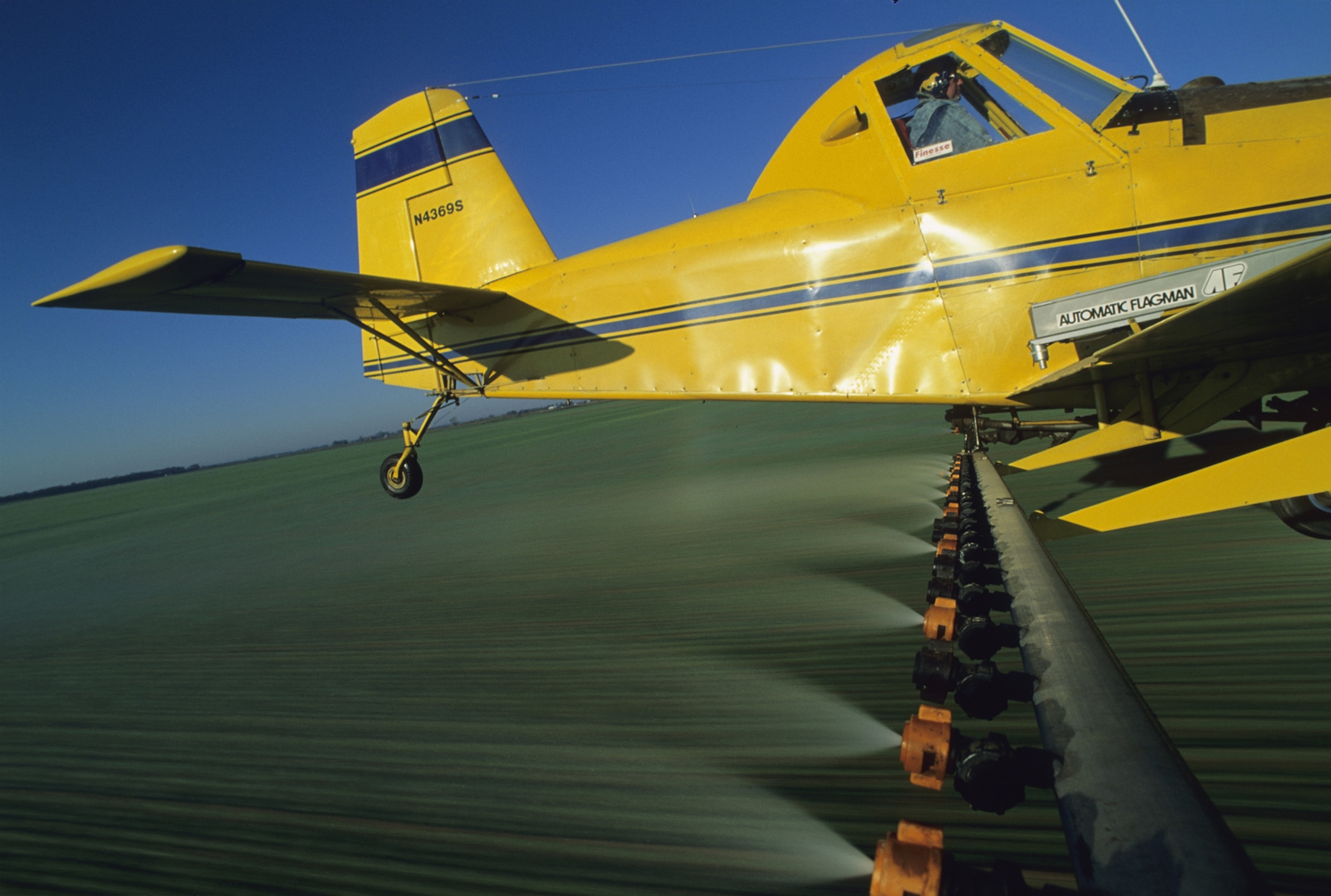 a crop duster spraying a winter wheat field with pesticides