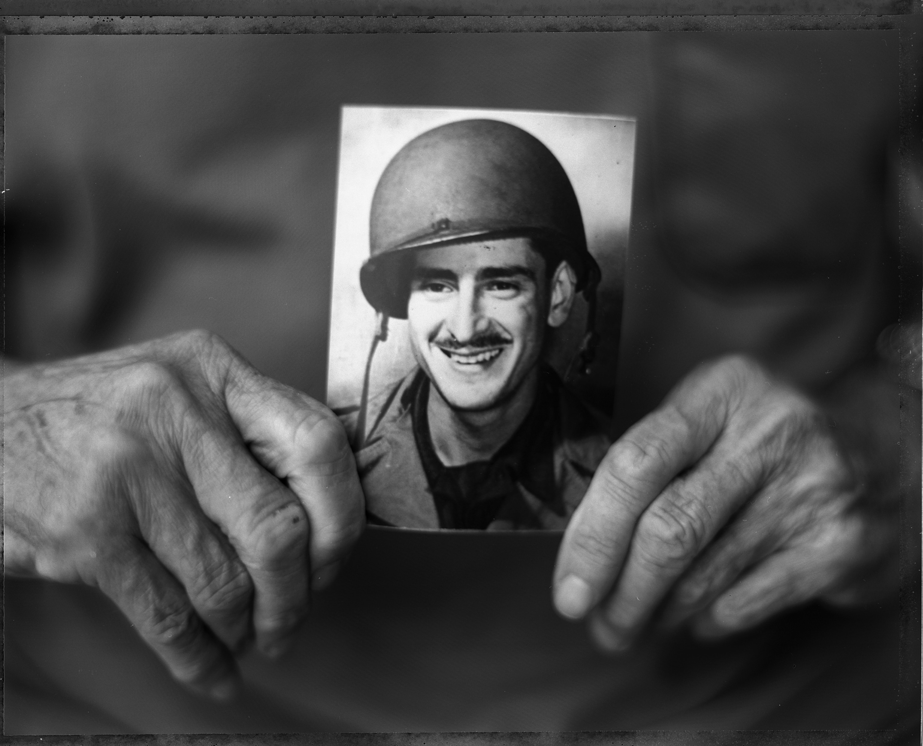Harry Parley, former flame thrower with the 116th Infantry Regiment, poses with a vintage photo of himself in the back yard of his house in Delray Beach, Florida in May 2004. Parley was in the first wave of troops going ashore at Omaha Beach in June 6, 1944 during the D-Day invasion of Europe. Parley passed away in 2008.