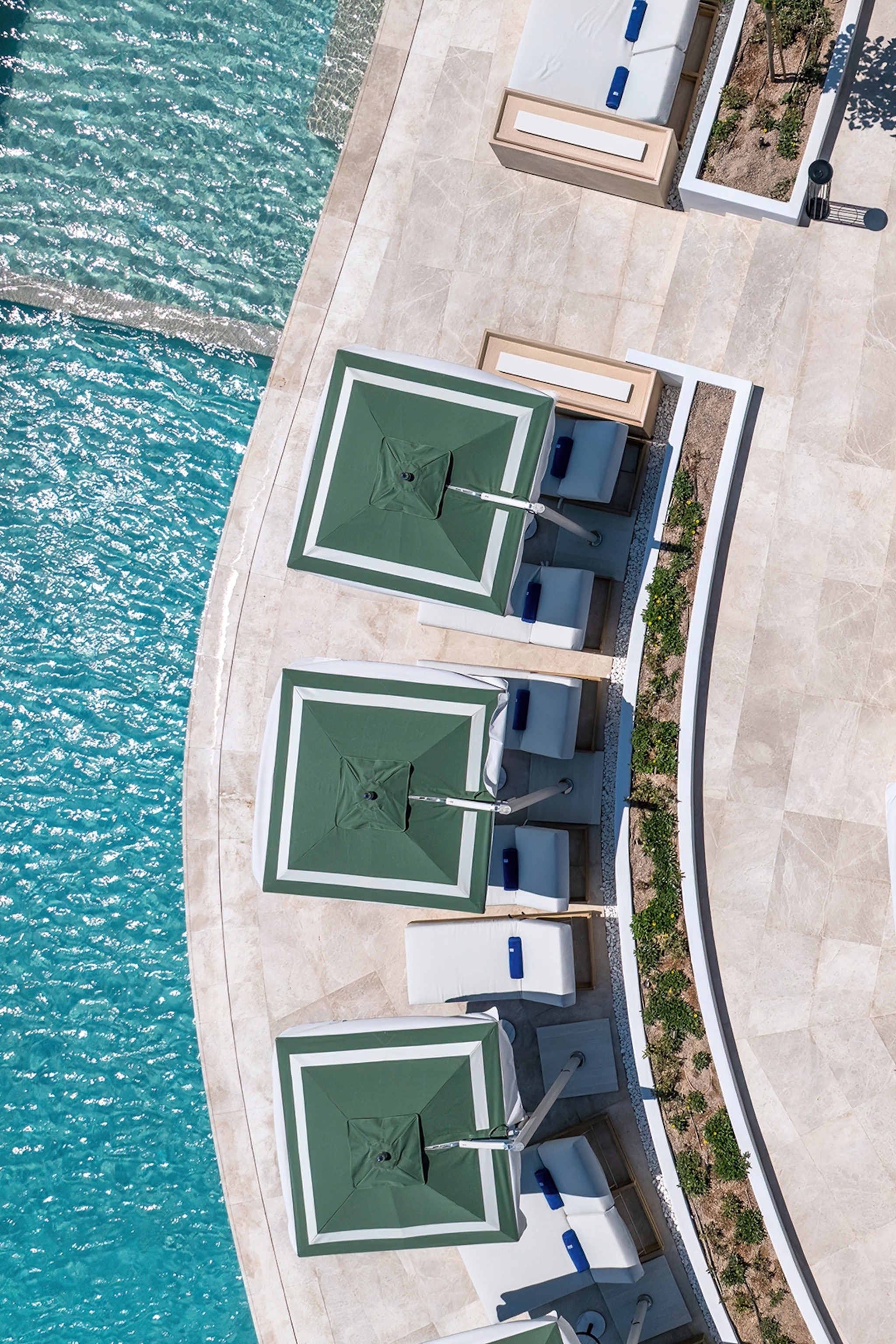 A curved pool shot from the air with sundecks lining the edge.