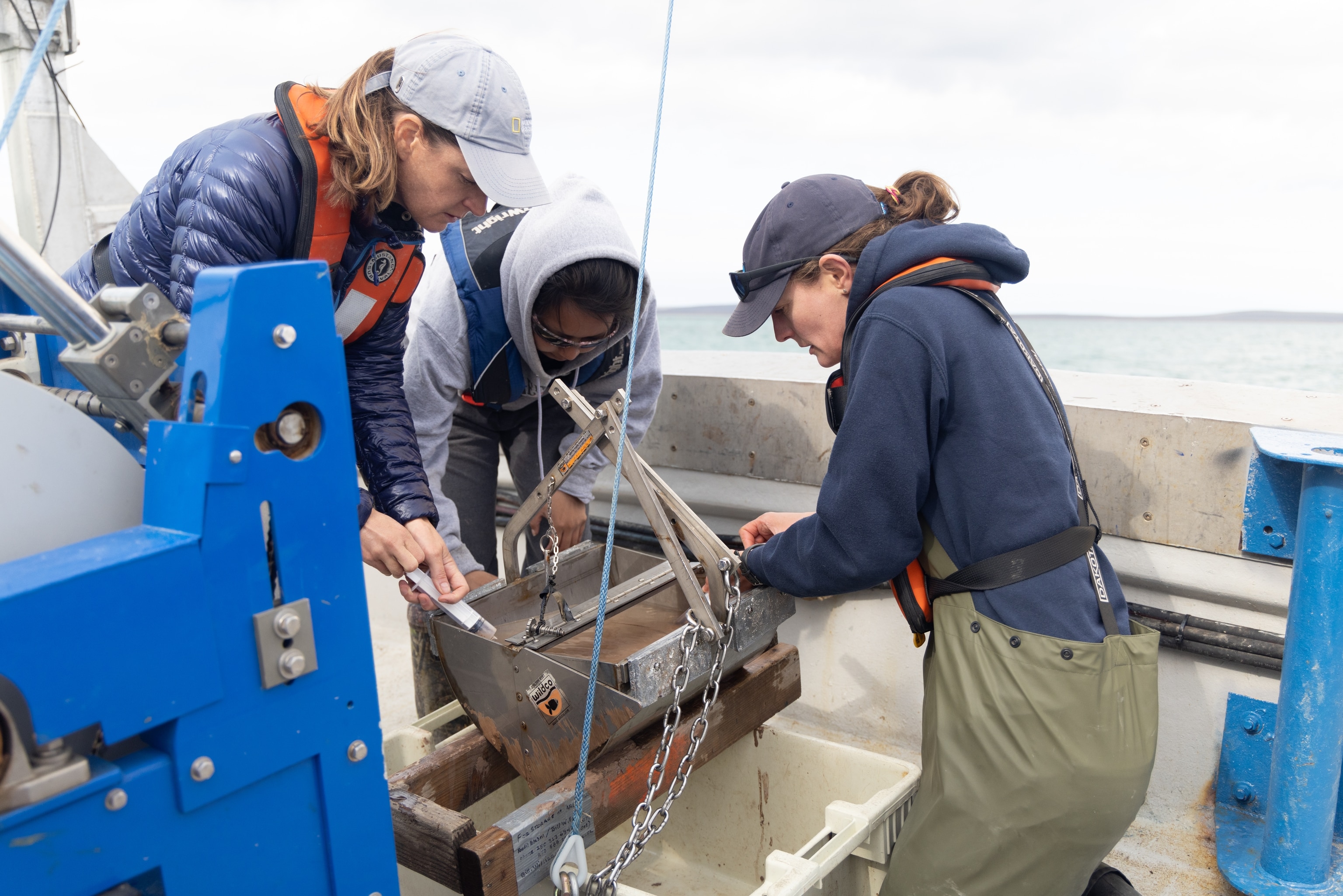 National Geographic Explorer and marine biogeochemist Kristina Brown (right) works with Director of Programs of Science & Innovation, Elizabeth Hogan (left), and Inuit youth member, Barbara Porter, to inspect a sediment-grab, while aboard the r/v Martin Bergmann.