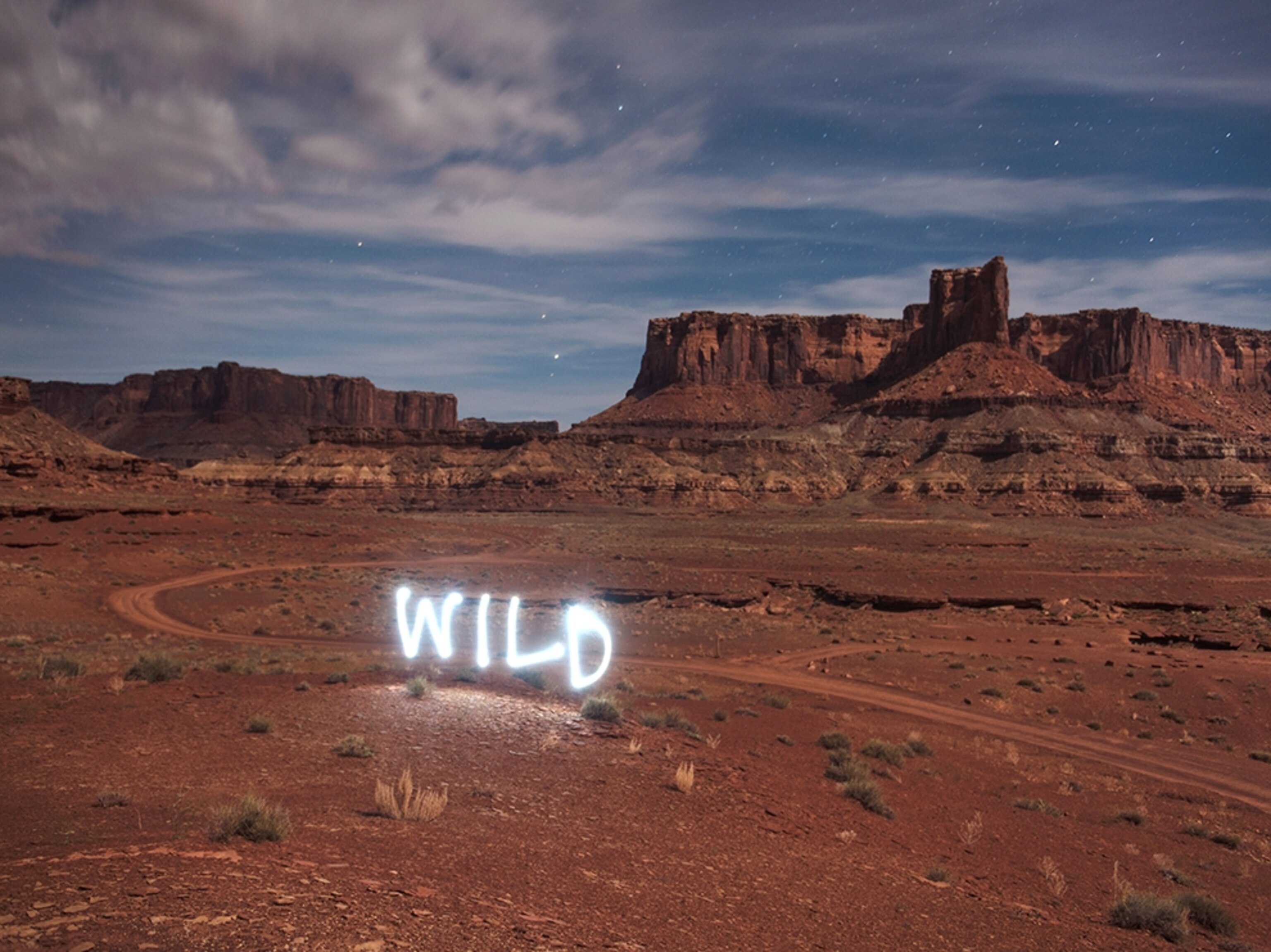 a someone using light trails from a flashlight to spell "Wild" using a long exposure in camera in Utah.