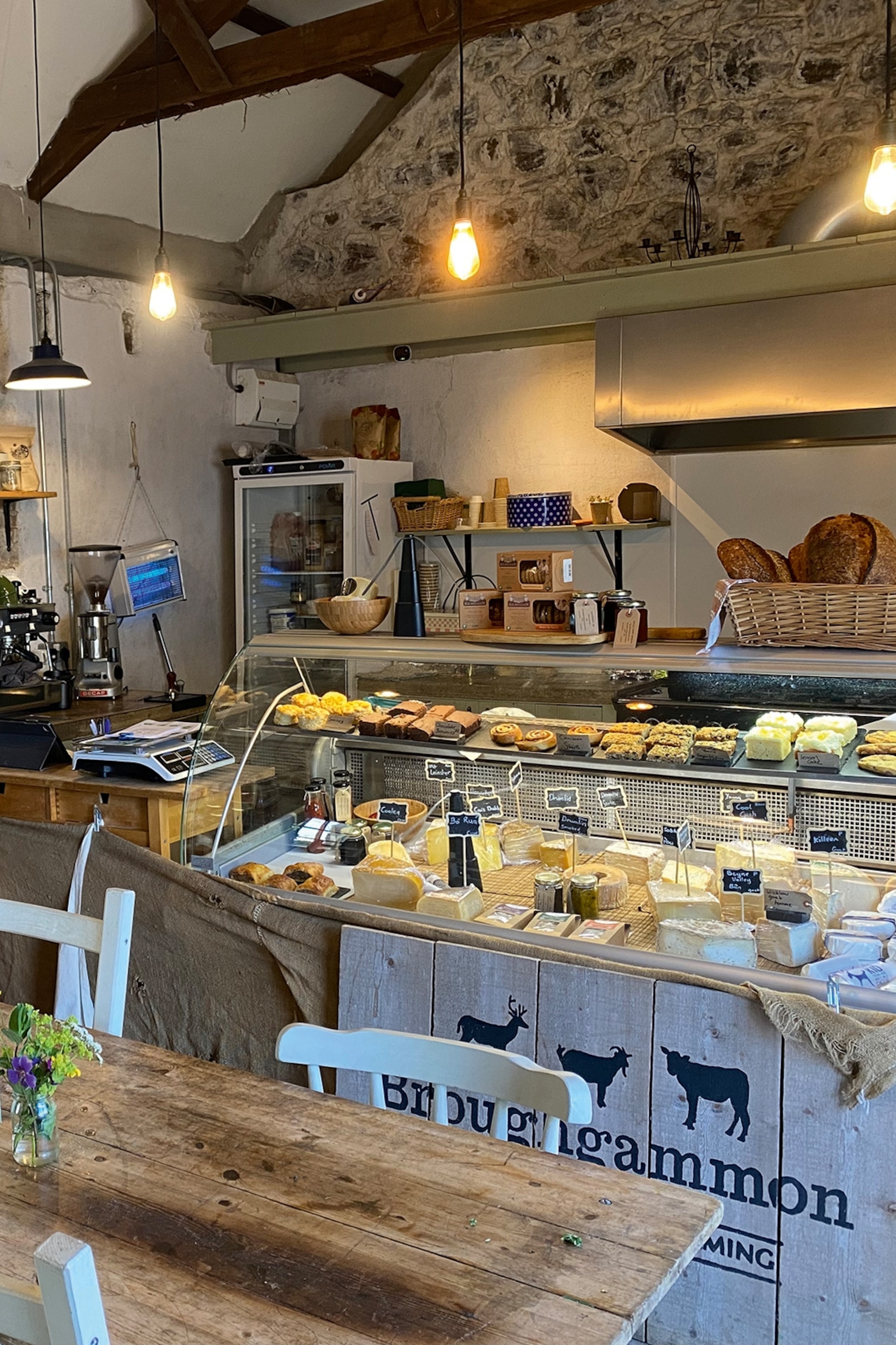The interiors of a charming farm shop with a counter bar displaying a wide selection of different cheeses.