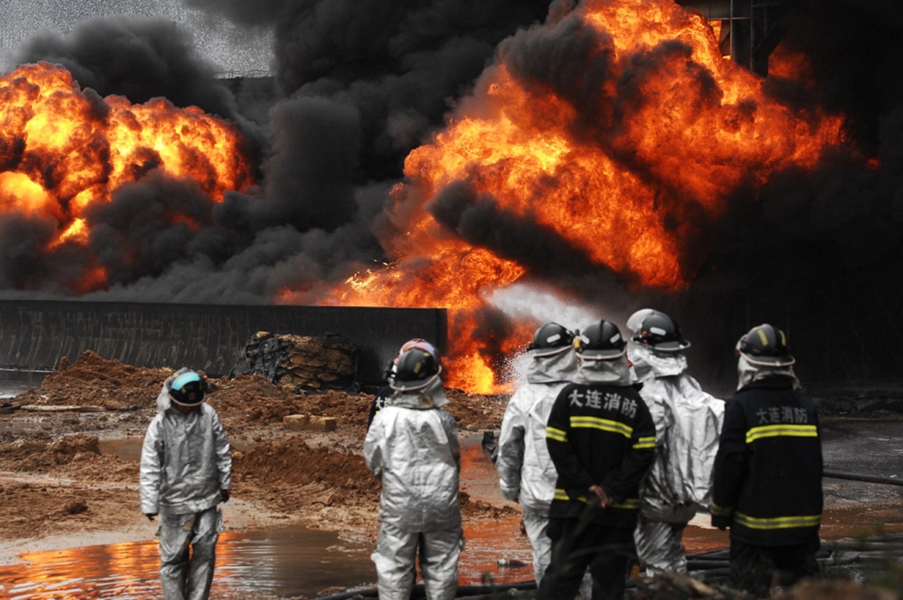 Firefighters attack blazes from the explosion that sparked the China oil spill