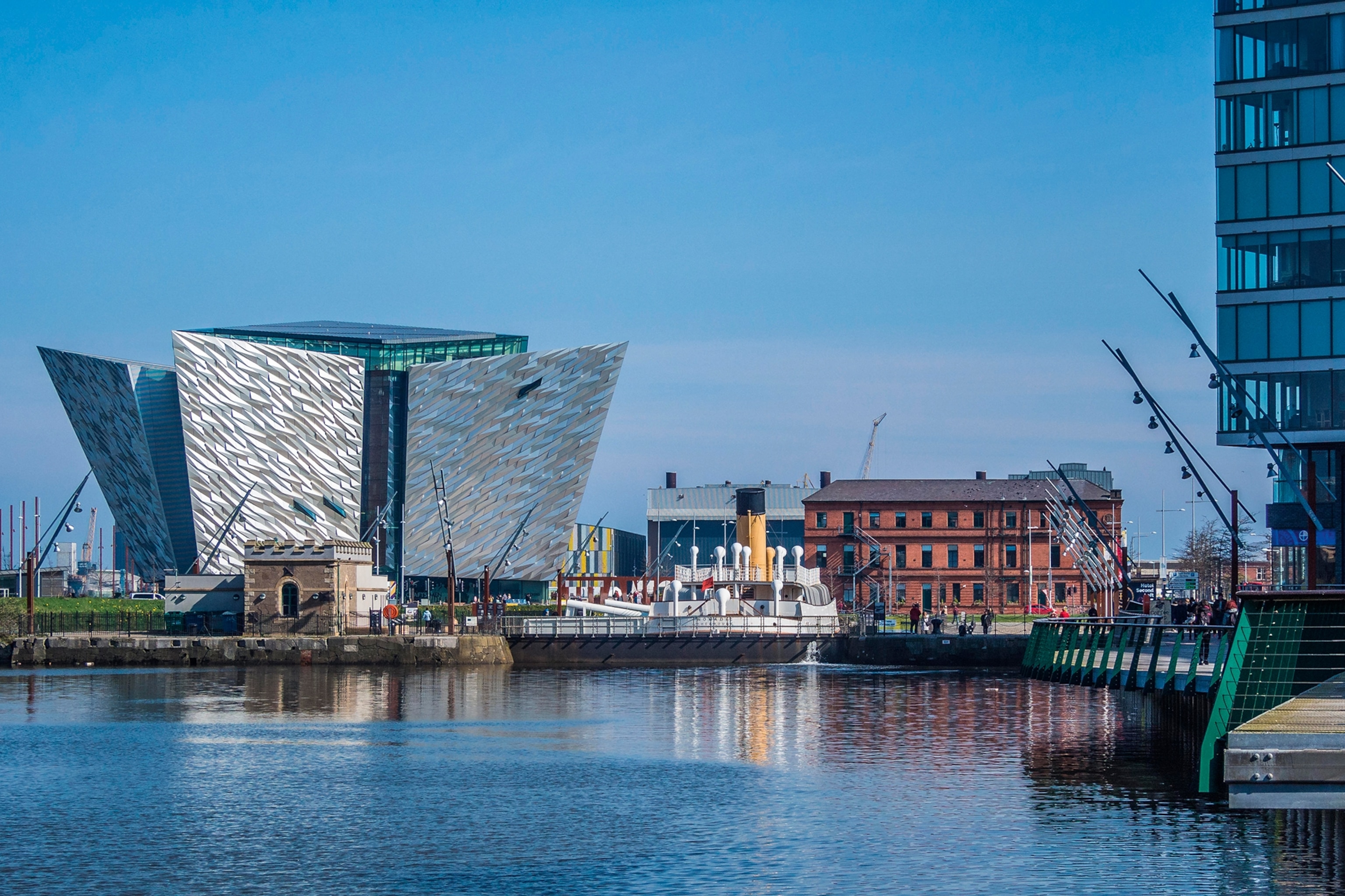 A modern museum at the edge of a harbour in the shape of a flat, inverted pyramid.