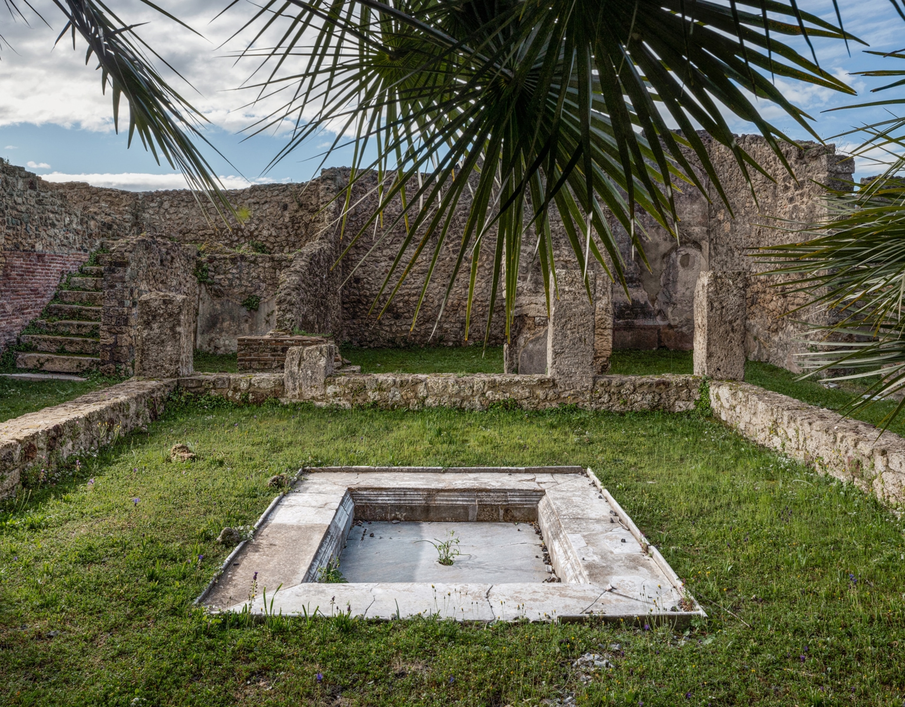 A small grass corridor with stone ruins around it