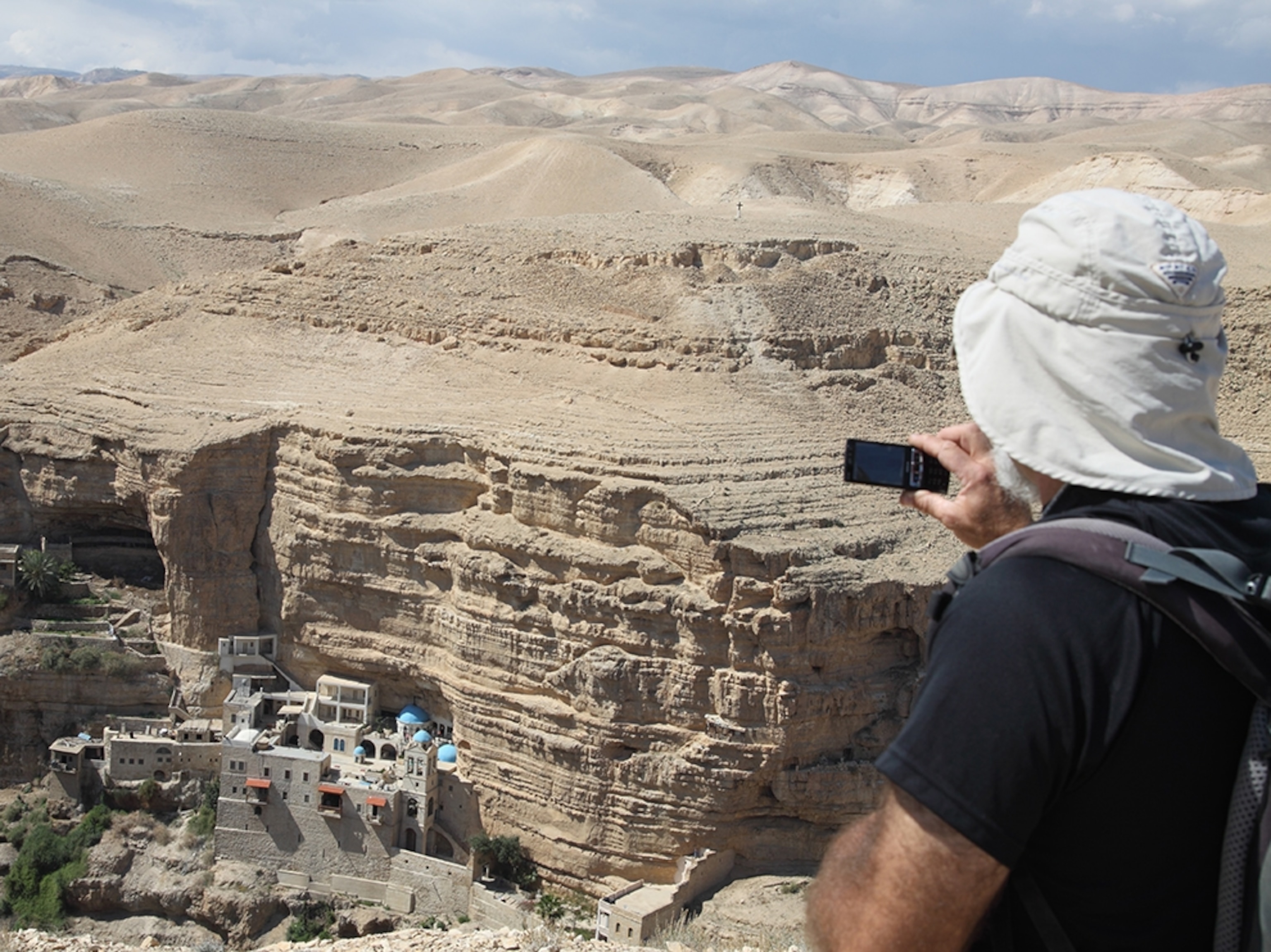 a hiker taking a photo of the monastery Saint George, near Jericho, Israel