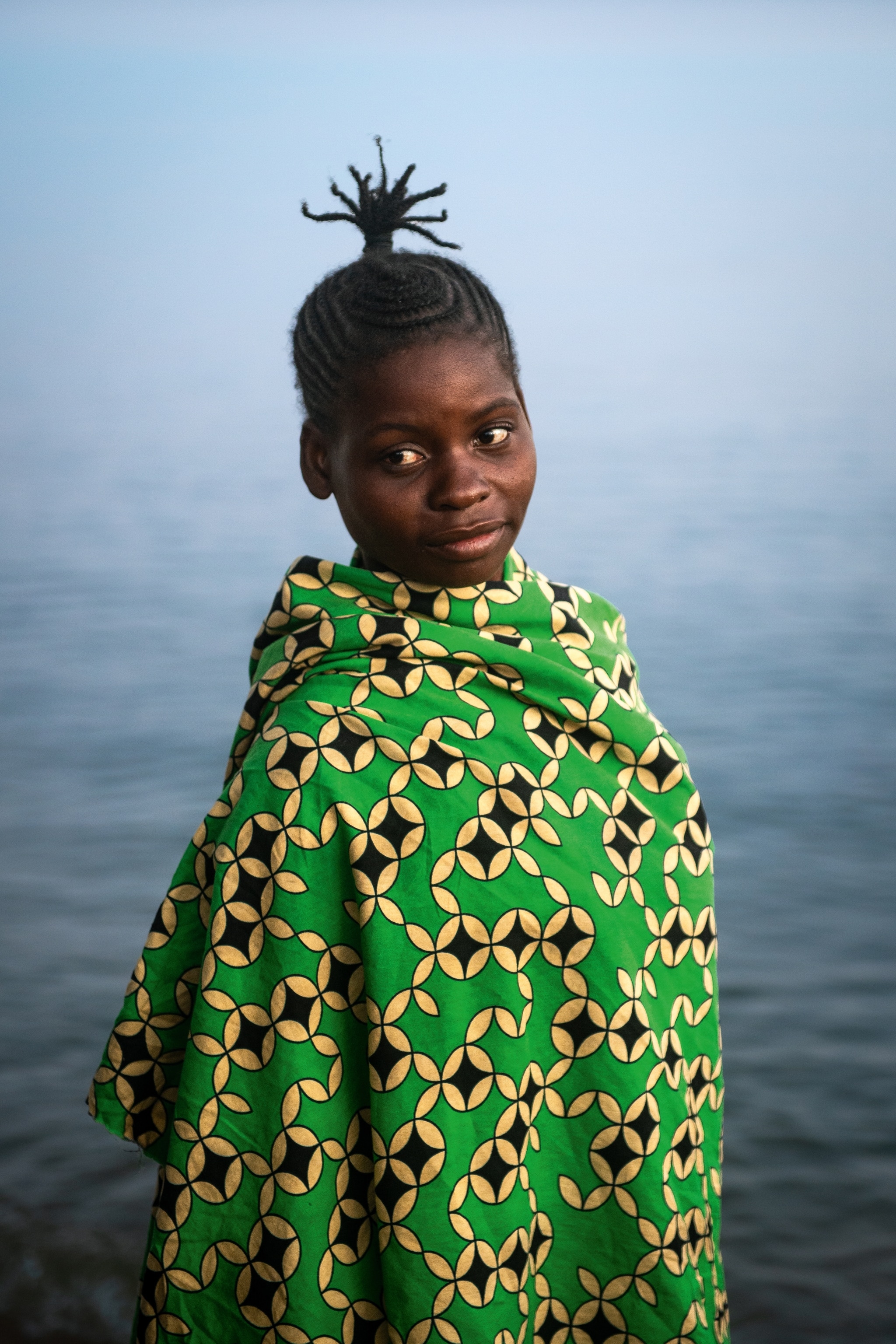 Person in green clothing waiting by the sea