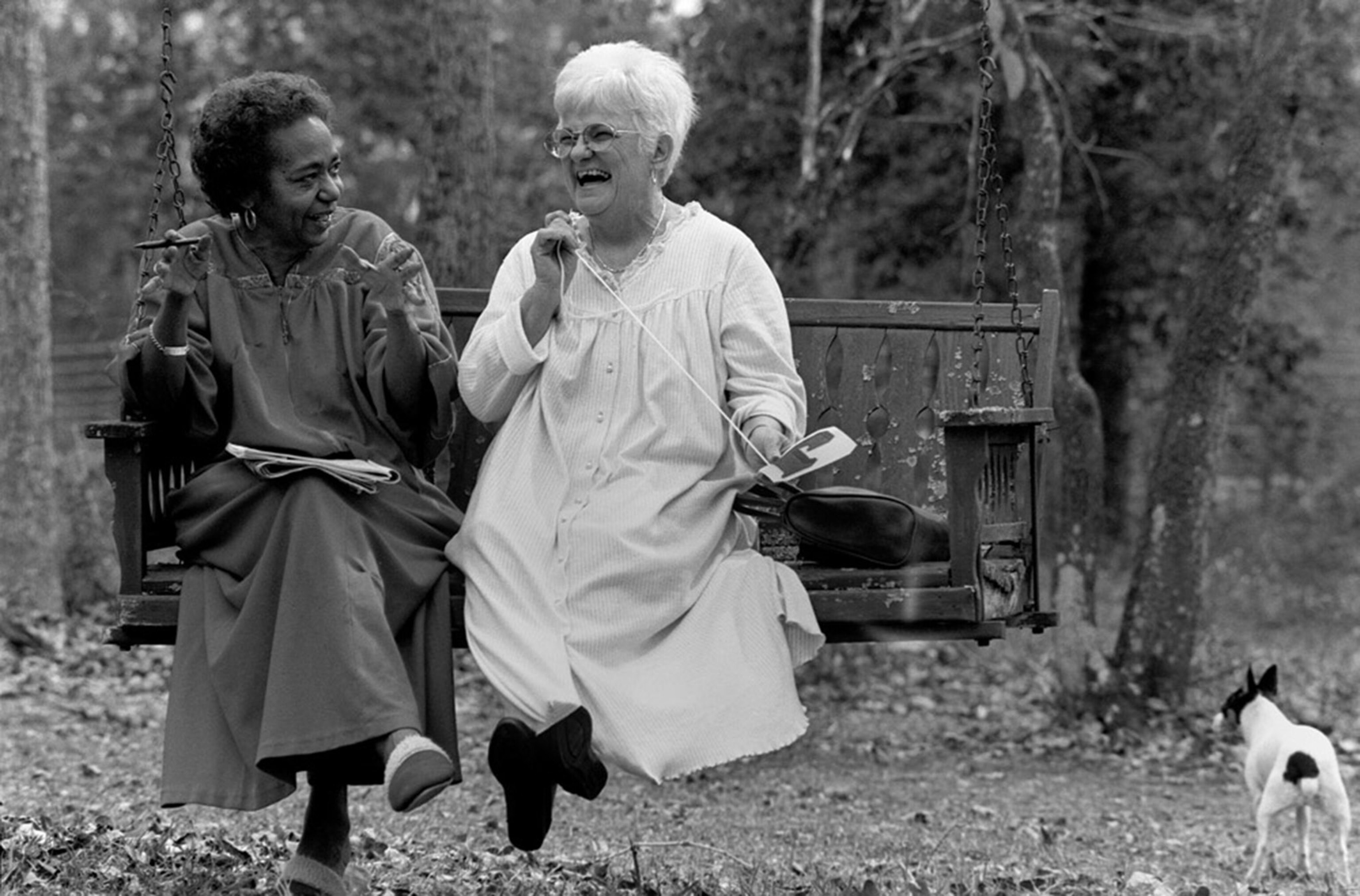 white woman and black woman on a swing in Jasper, Texas, laughing.