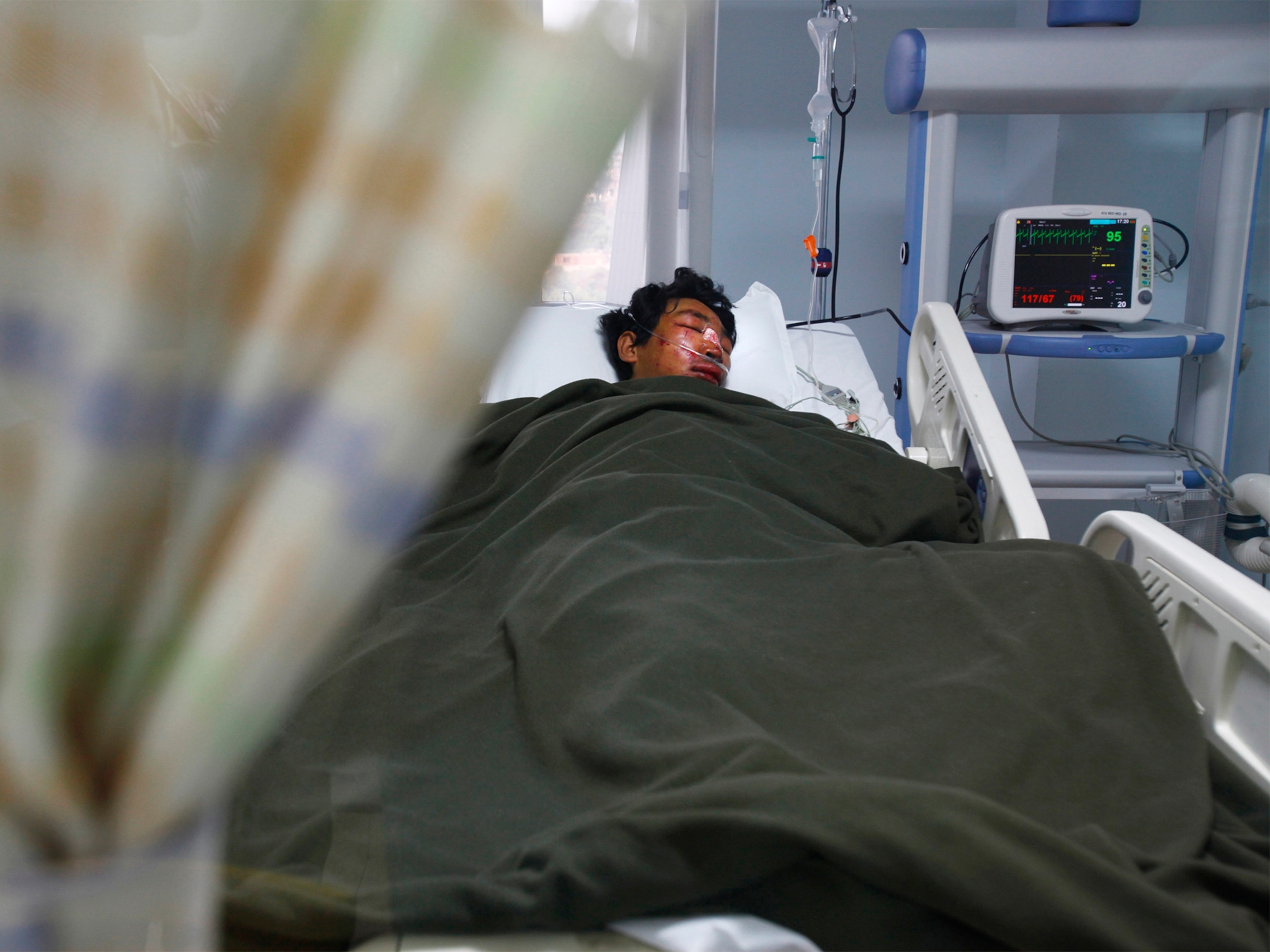 an injured sherpa lying in a hospital bed.