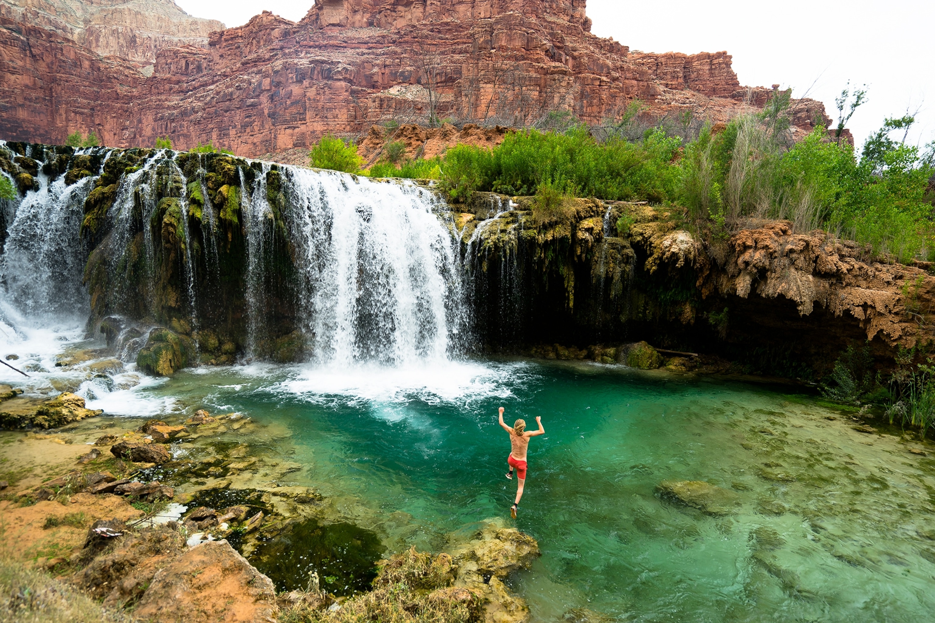 man jumping into water near waterfall, Havasupai Reservation, Arizona