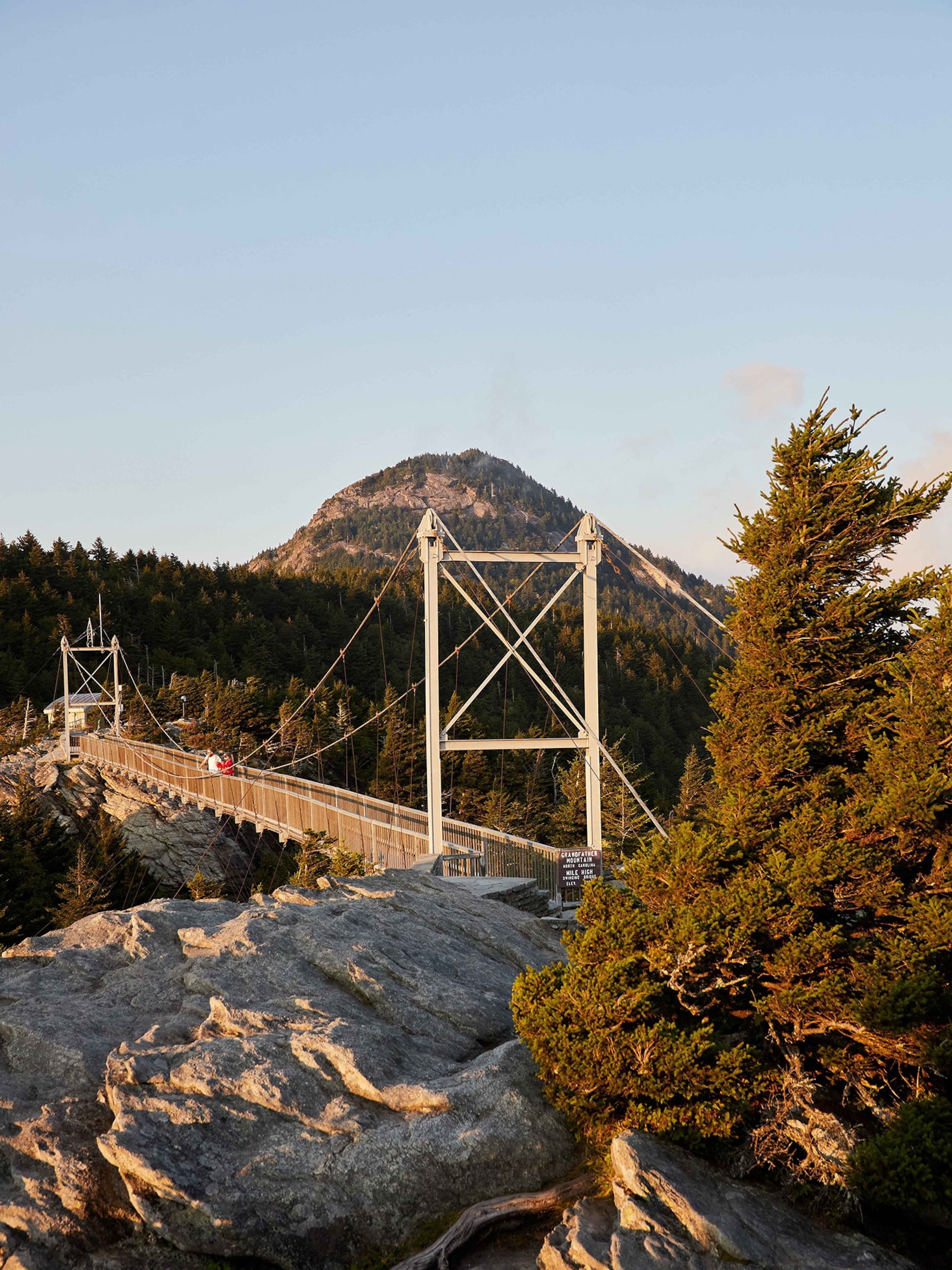 A bridge with people looking out with a mountain in the back.