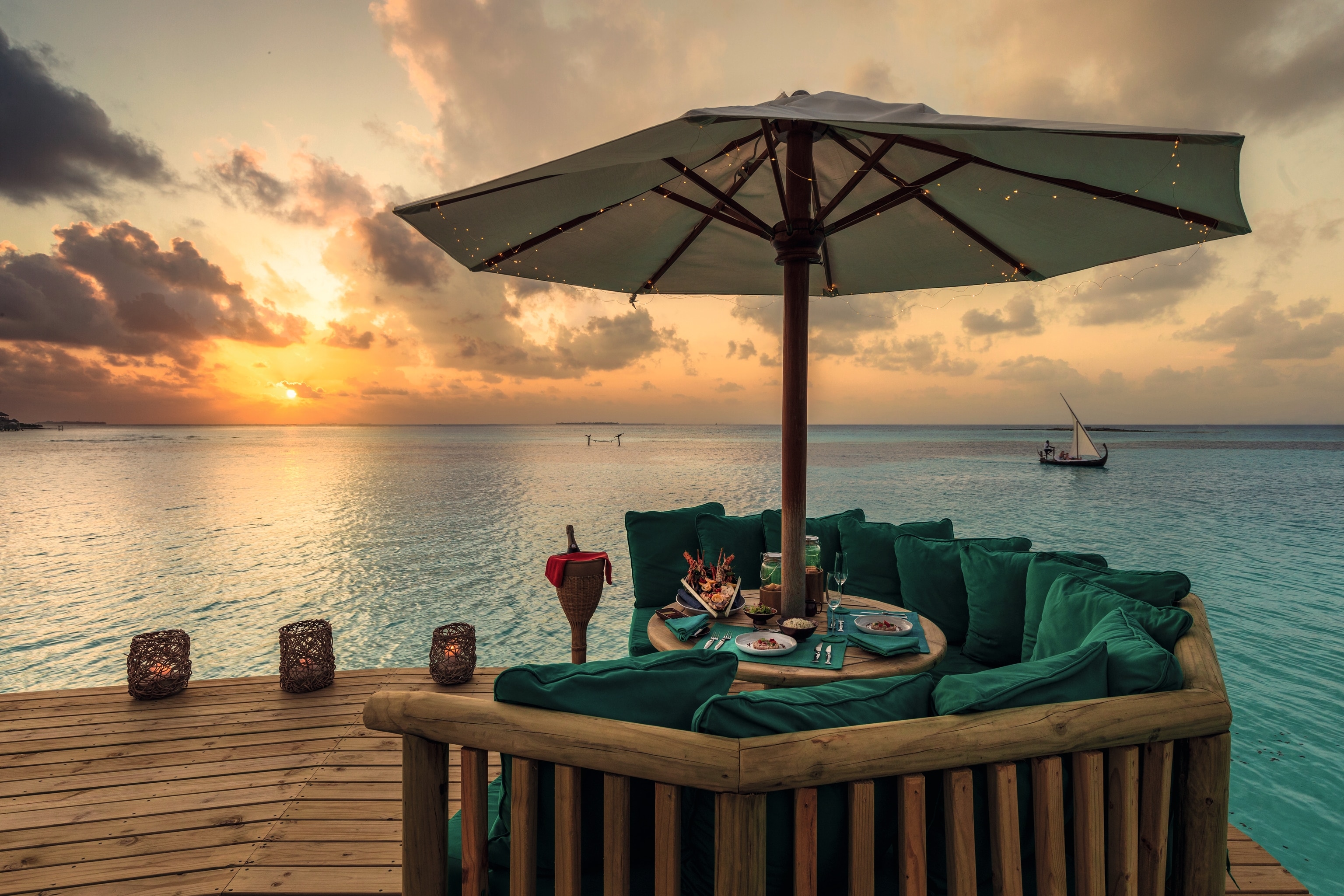 A large round table with a plush seating area and canopy overlooking the ocean 