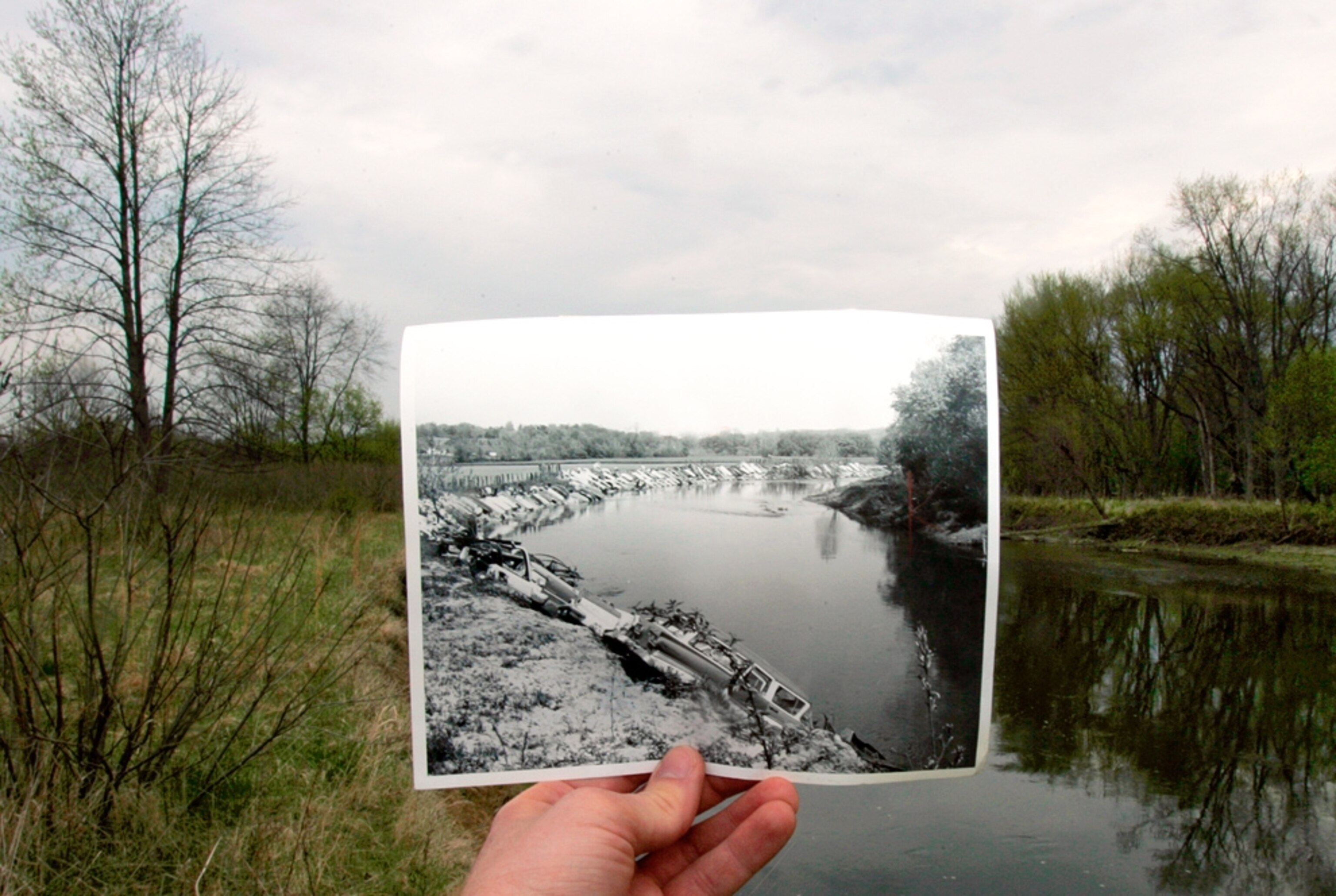 A 1967 photograph showing garbage in the Cuyahoga River is held in front of the cleaned-up river in 2006