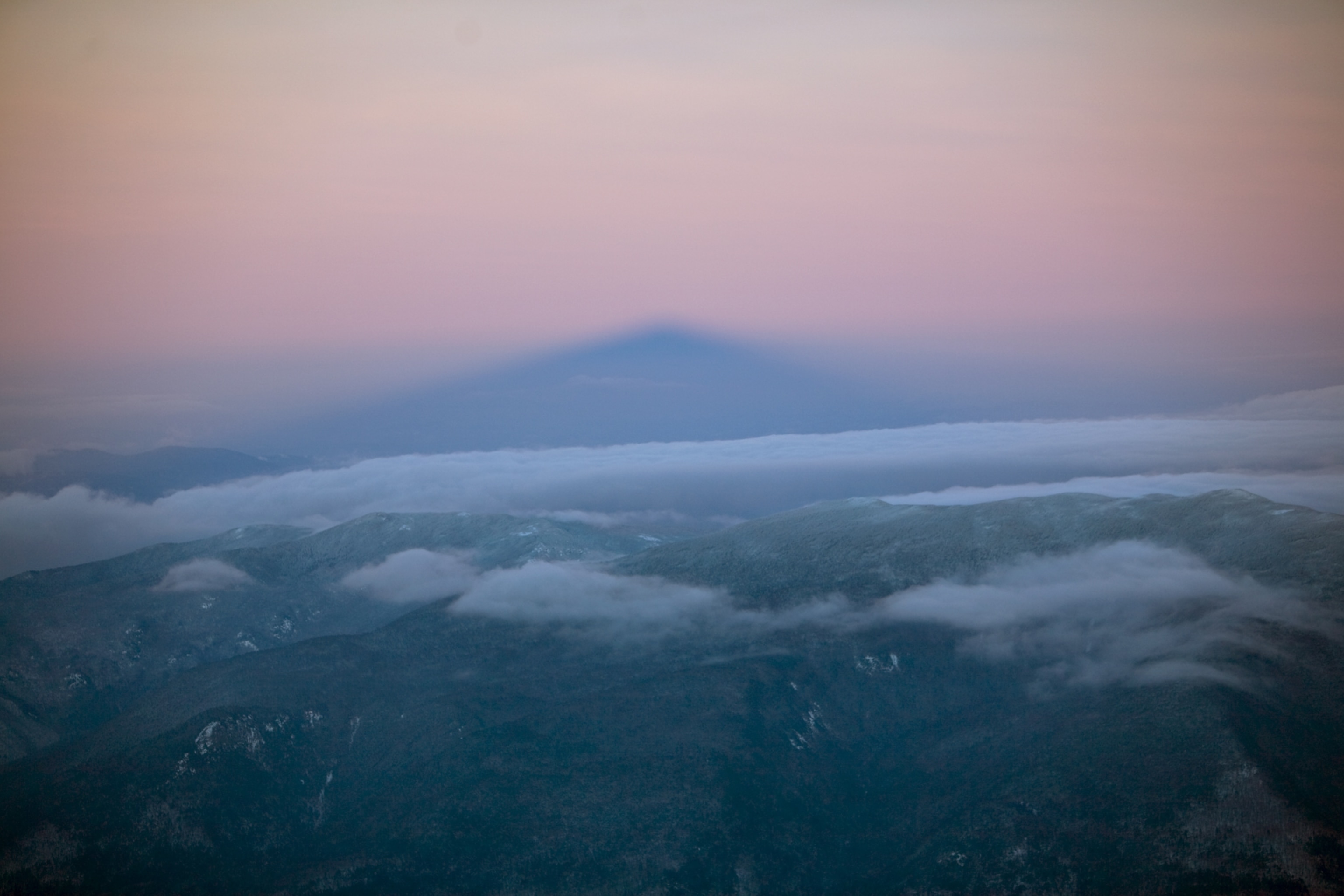 a winter sunrise casting Mount Washington's shadow across White Mountain National Forest