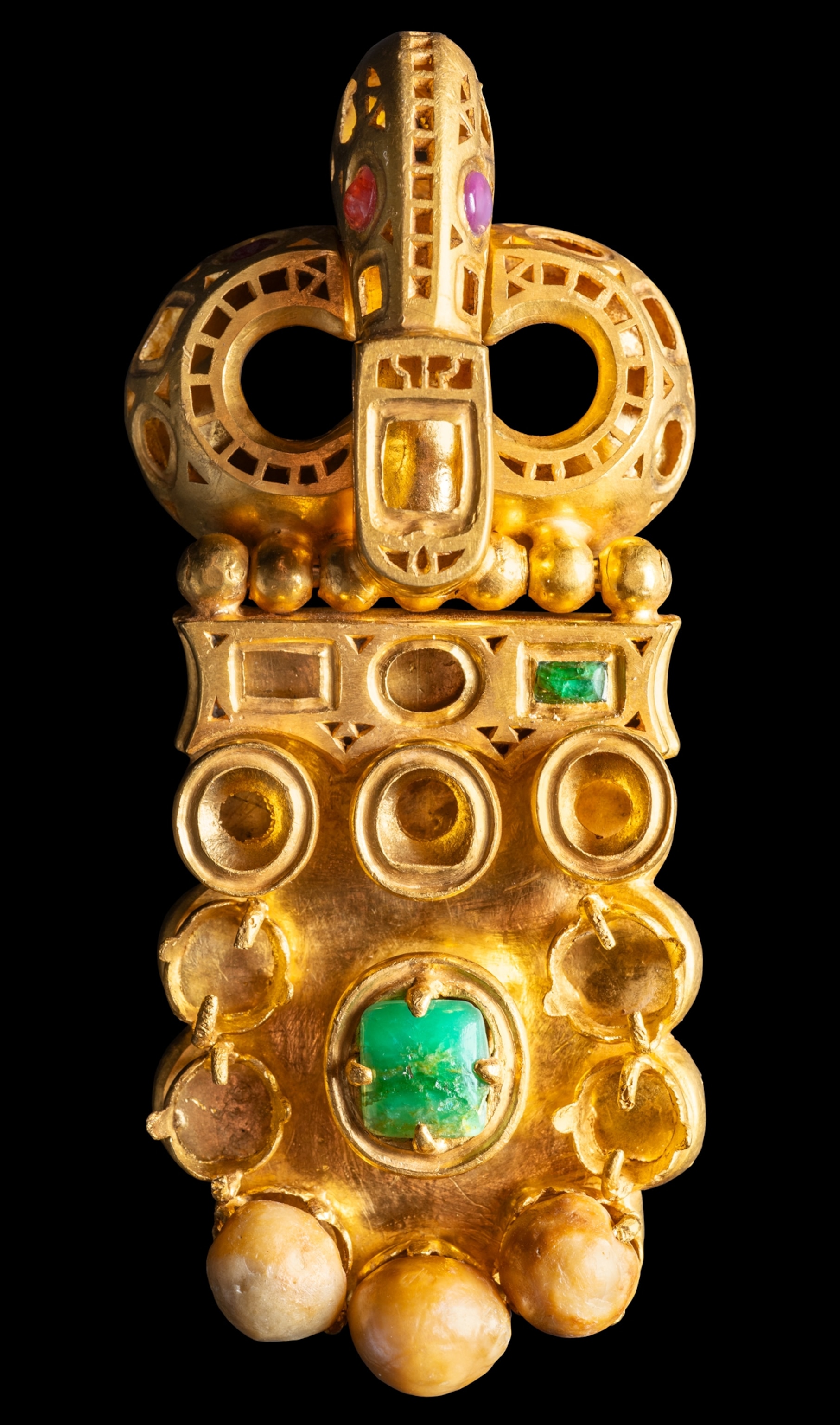 An artifact with various green, purple, and red gem stones that has been restored to a shiny, gold color with visible gemstones.