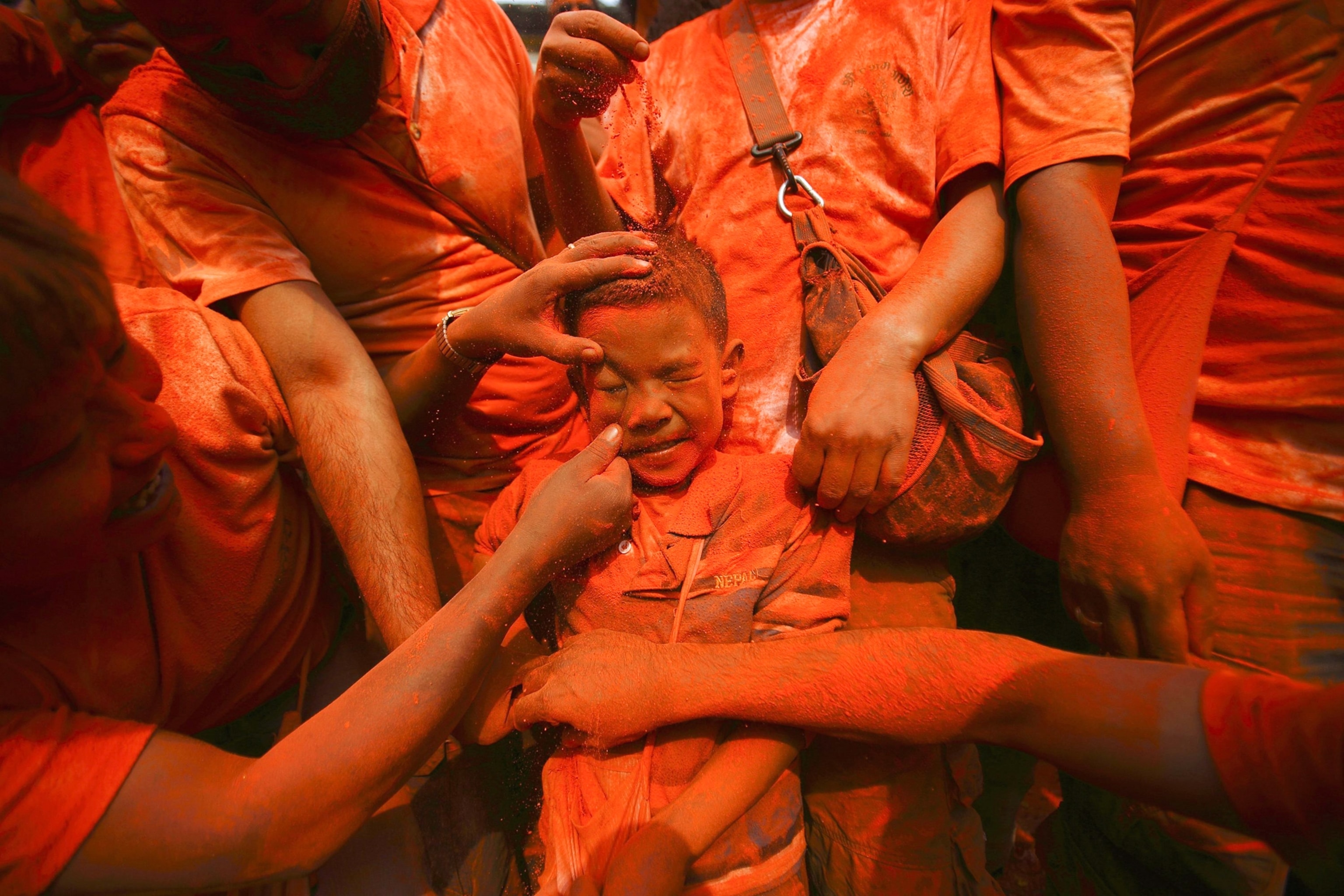 a boy being smeared with colorful powder in Nepal.