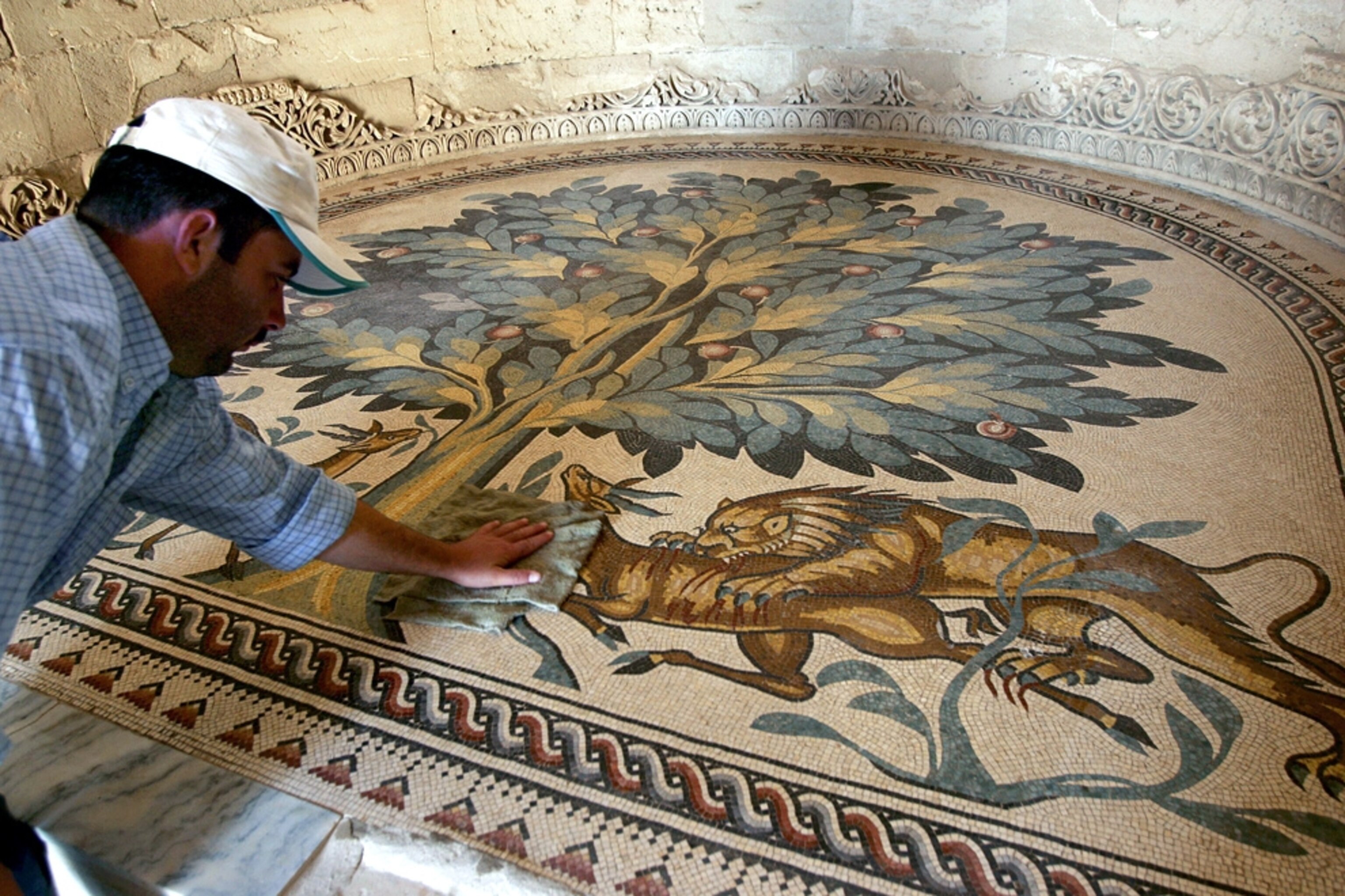 Picture of a man cleaning a mosaic floor in an ancient palace in Jericho.