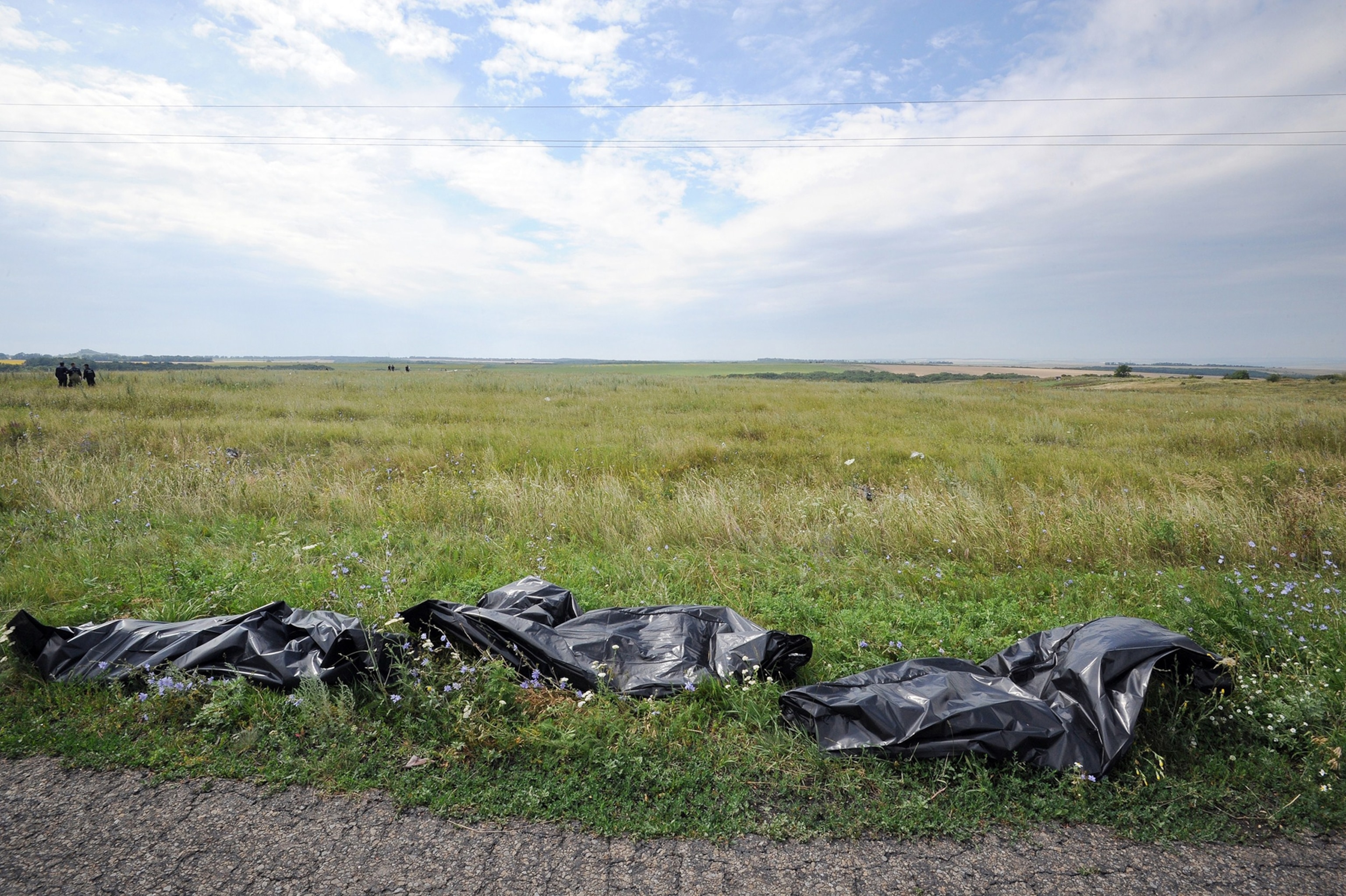 Bodies of victims wrapped in bags wait to be collected by rescuers on the side of the road at the site of the crash of a Malaysia Airlines plane carrying 298 people from Amsterdam to Kuala Lumpur in Grabove, in rebel-held east Ukraine, on July 19, 2014.