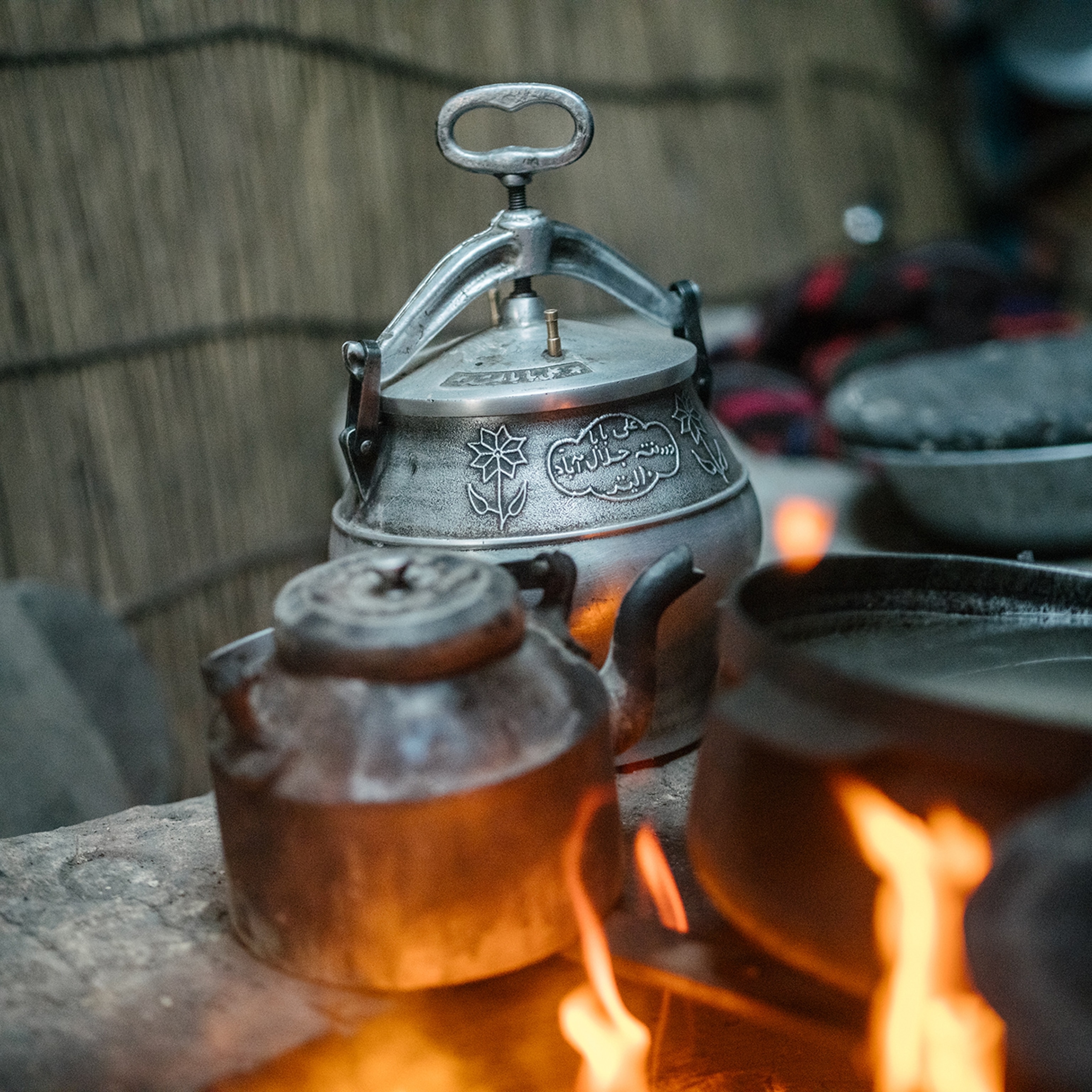Various cooking devices sit on the ledge of a fire pit inside a yurt