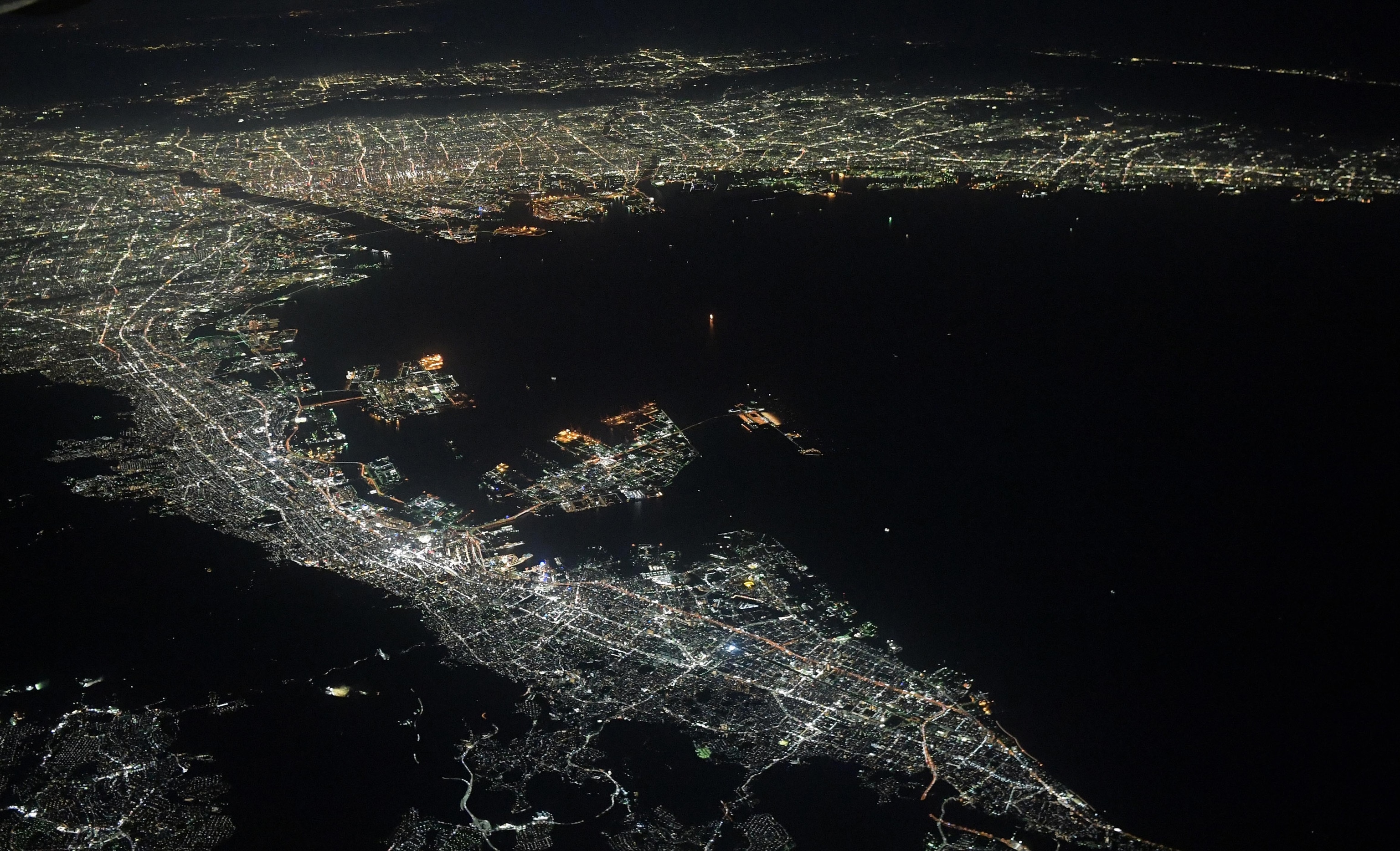 Aerial photo of Osaka Bay and surrounding cities at night.