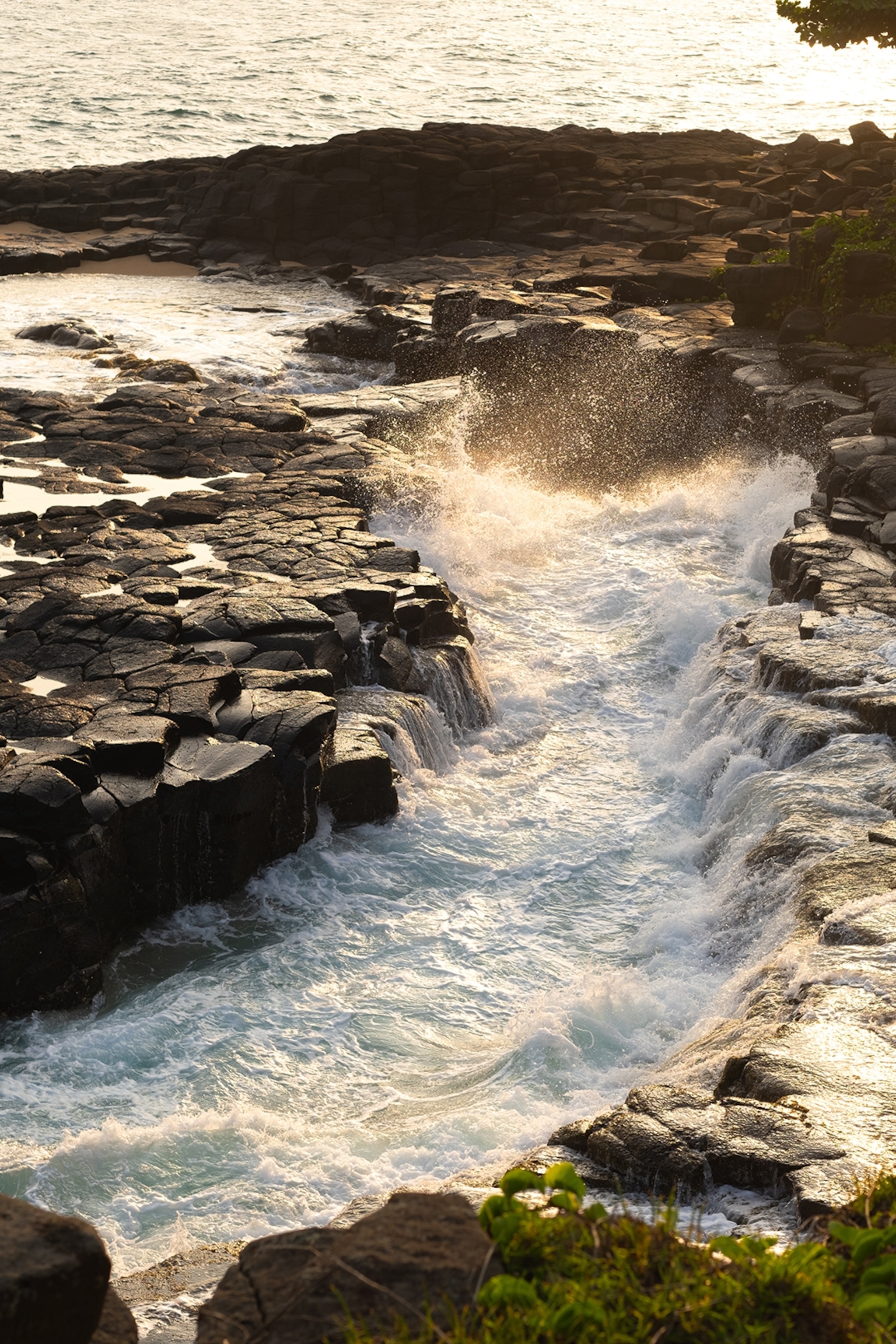 A close-up of water crashing into the rocky coastline.