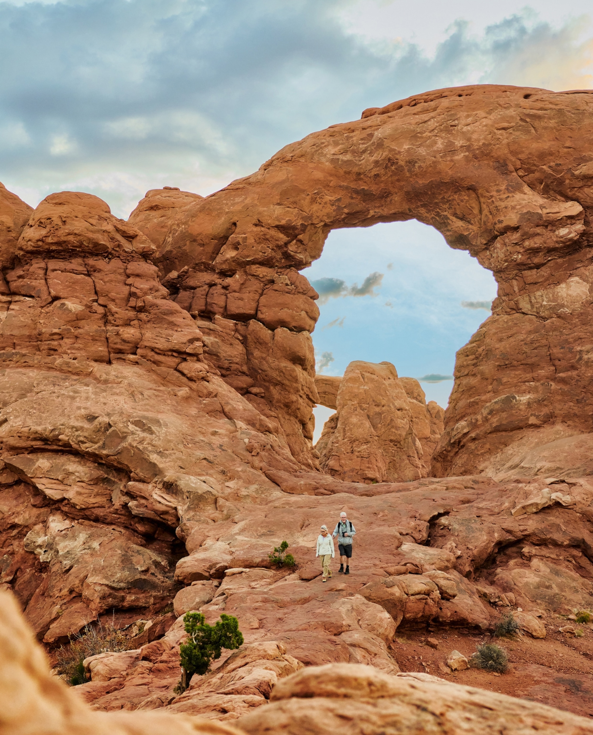 A couple walks among large red rocks