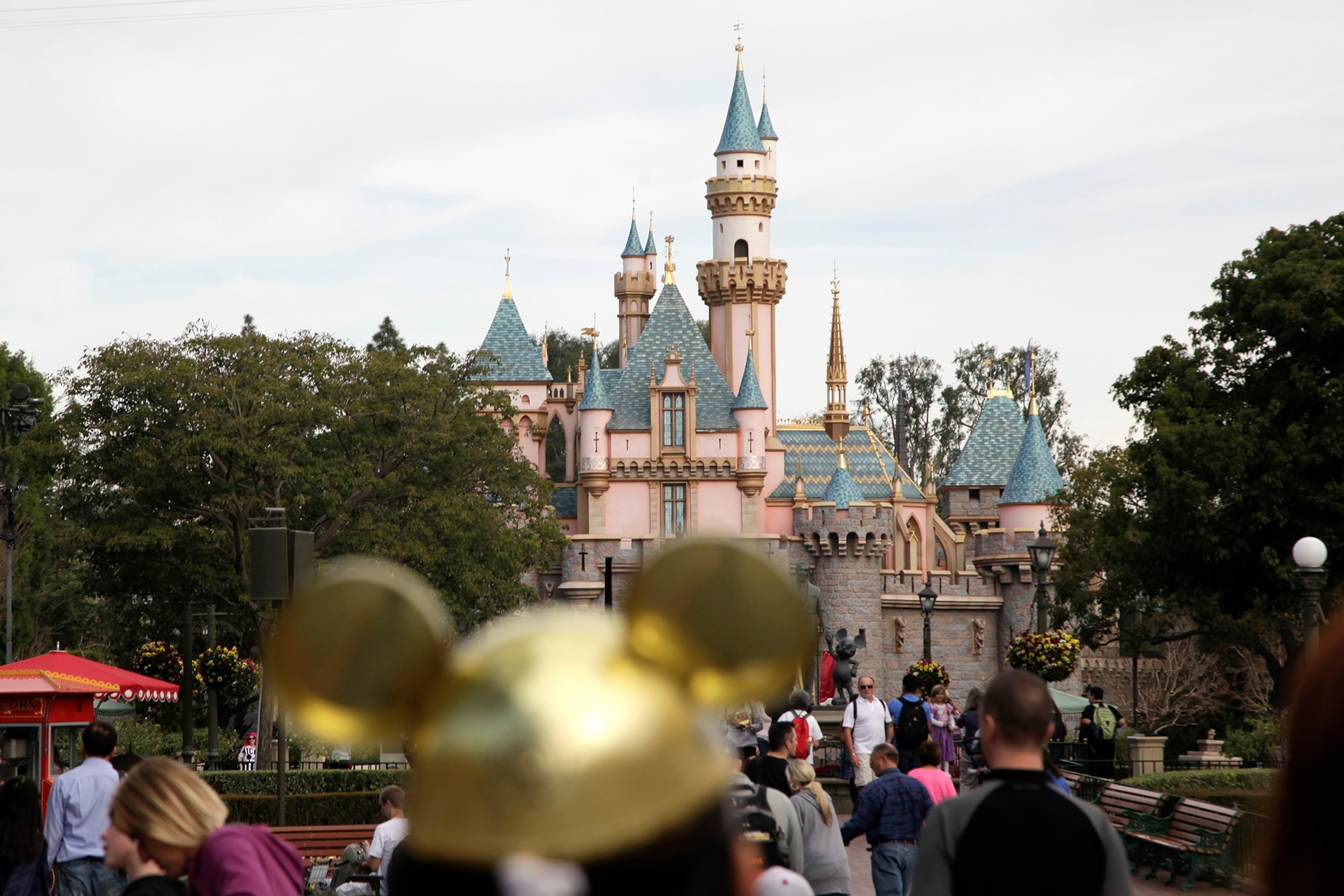 people walk toward the Sleeping Beauty's Castle in the background at Disneyland