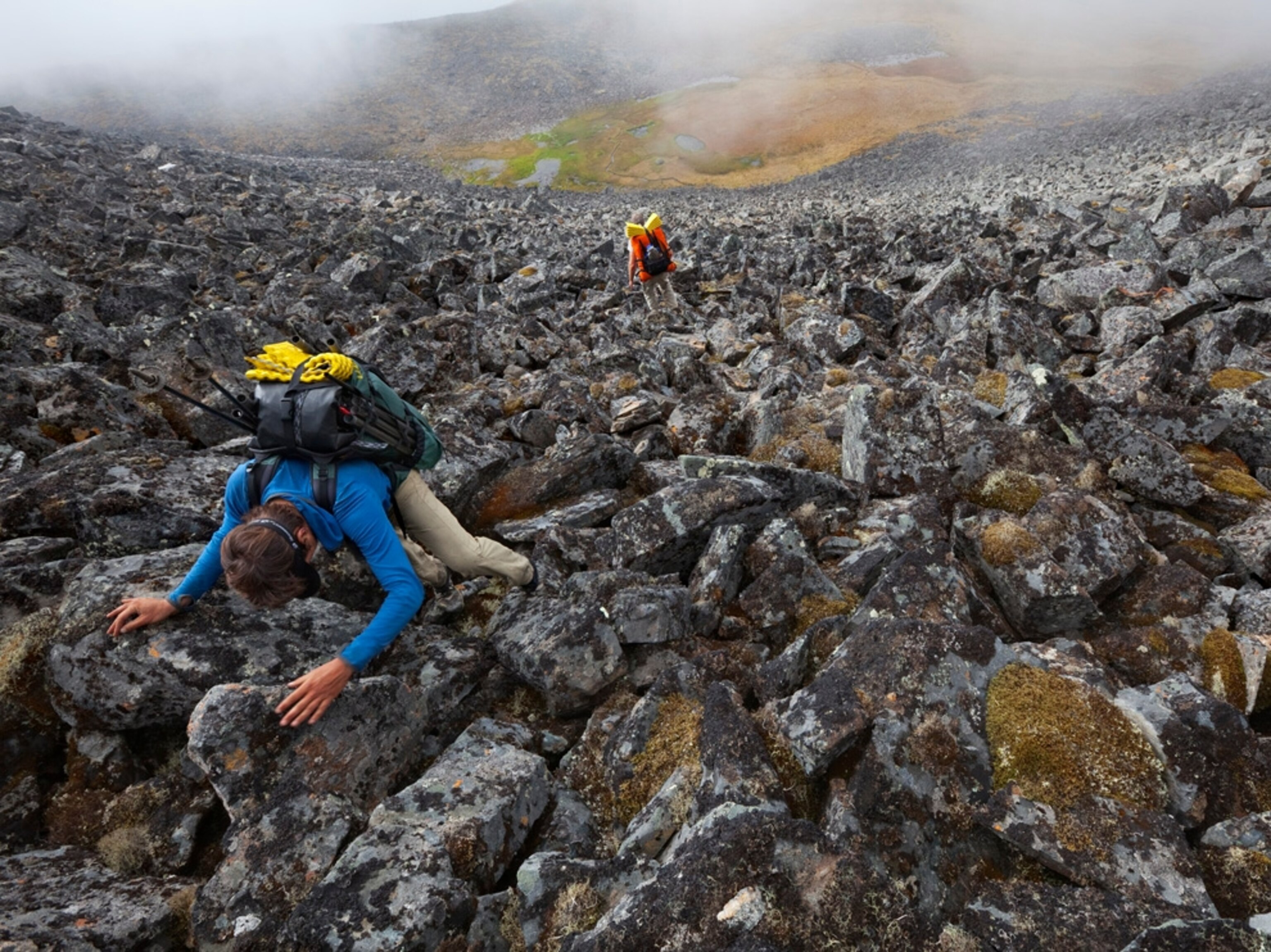 A pair of hikers climbing a boulder-strewn pass in Alaska