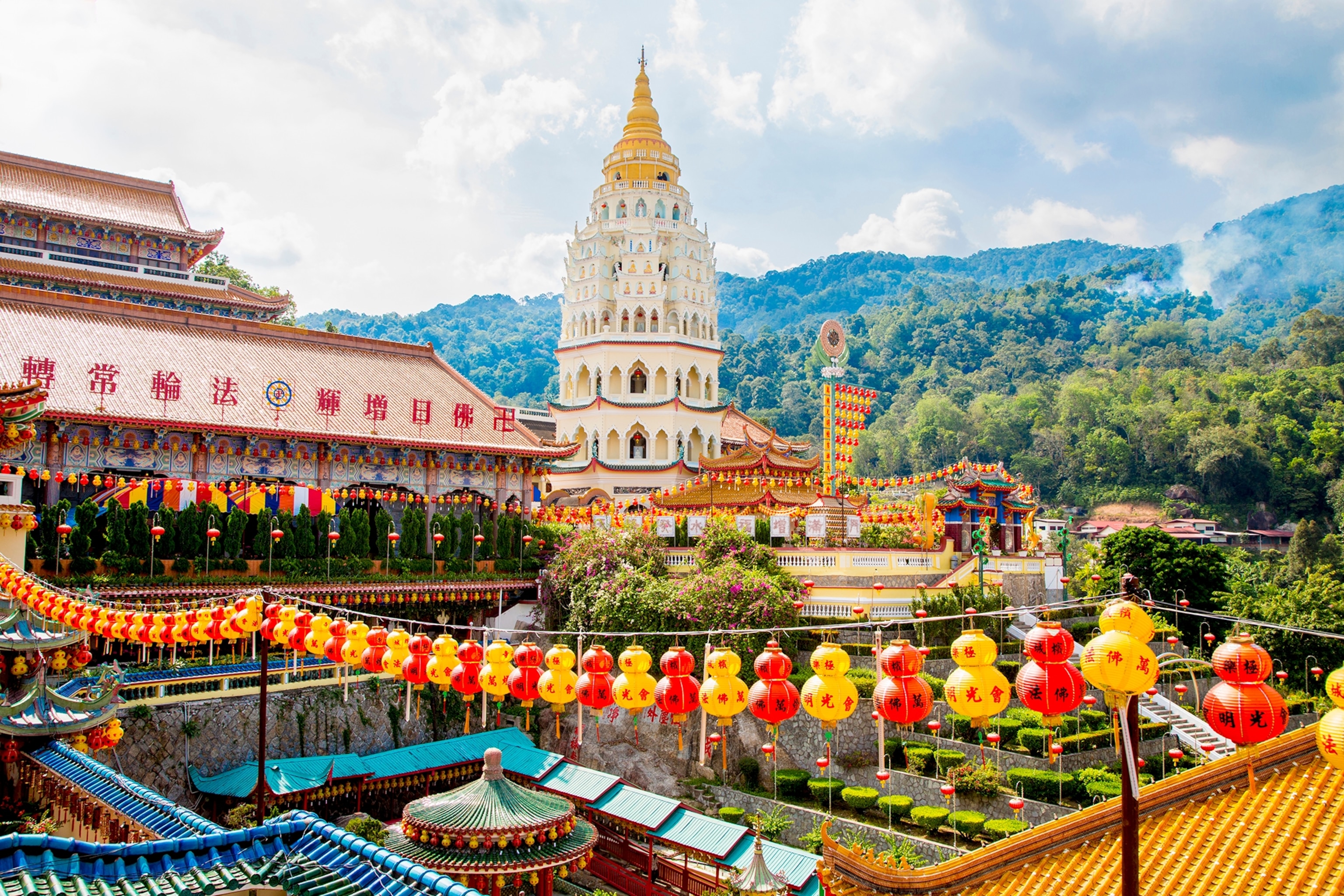 A Malaysian tower shot across the roofs of a vibrant city with lanterns hung in between.