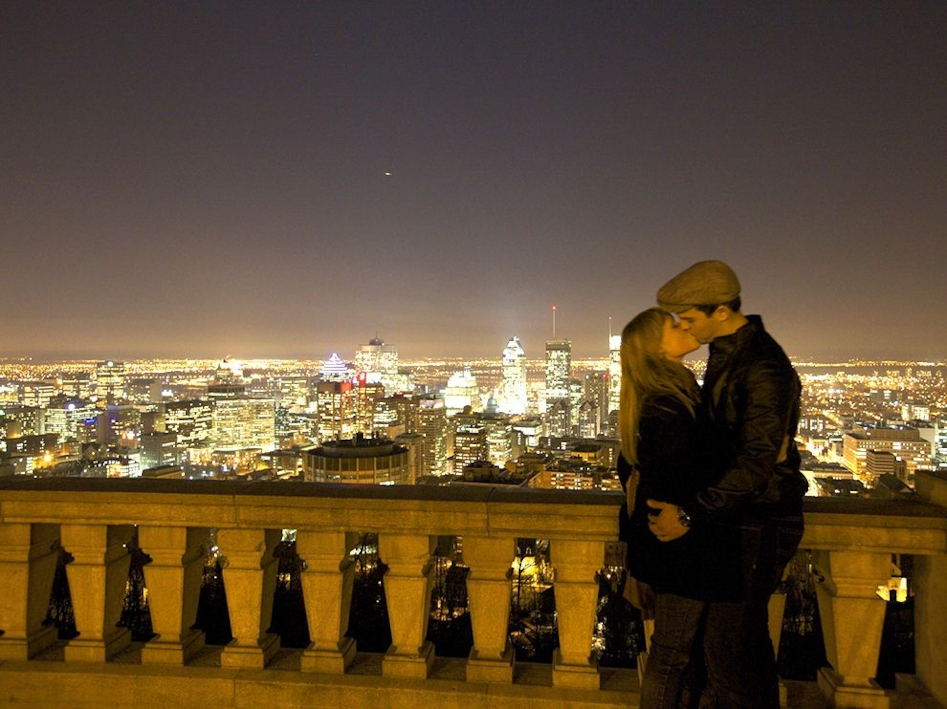 a couple sneaking a kiss atop Mount Royal in Montreal