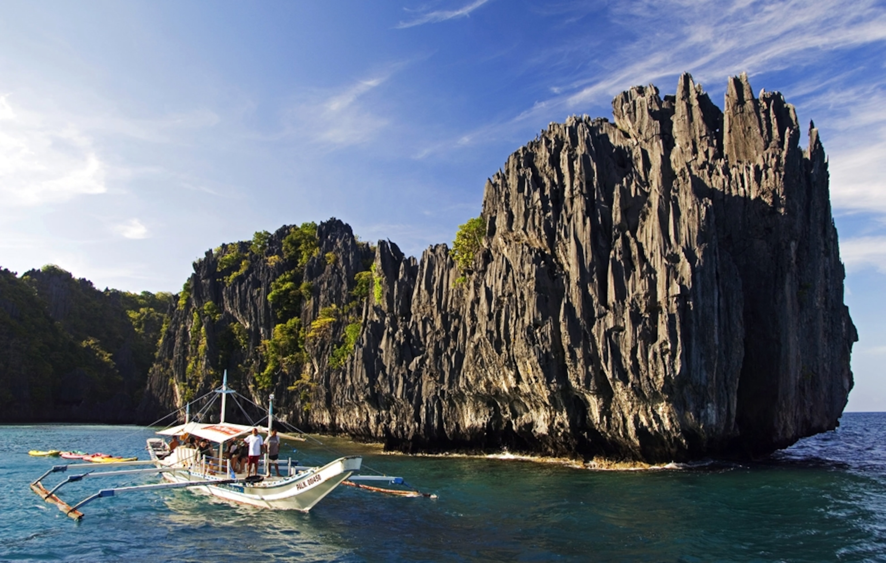 Boat passing rocky cliff