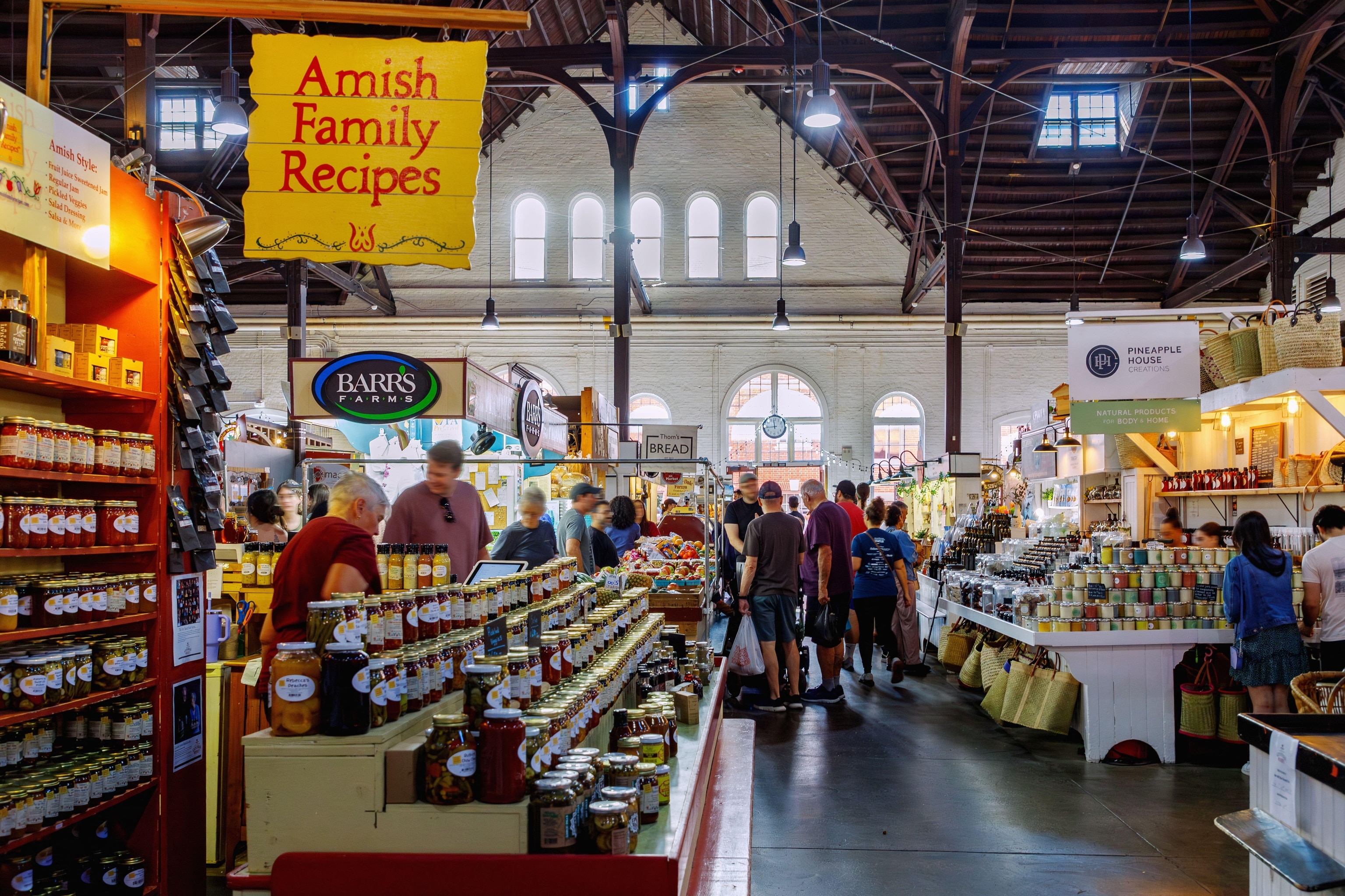 A wide view of people shopping at a farmers market with multiple booths