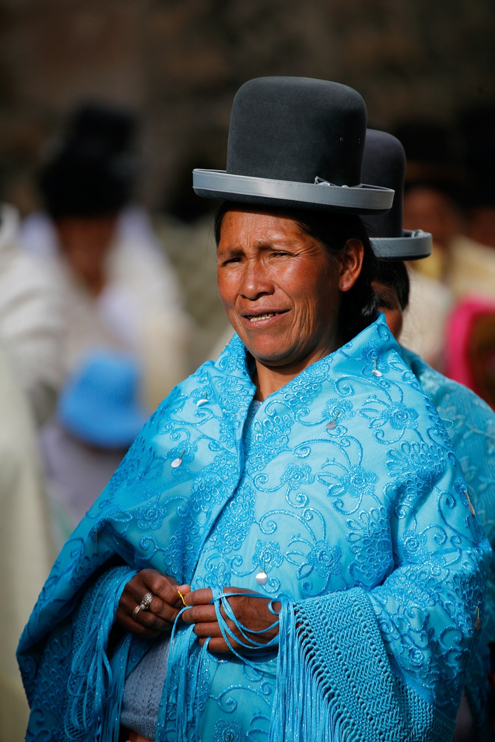 An elderly Bolivian woman dressed in an embroidered scarf and wearing an English bowler hat.