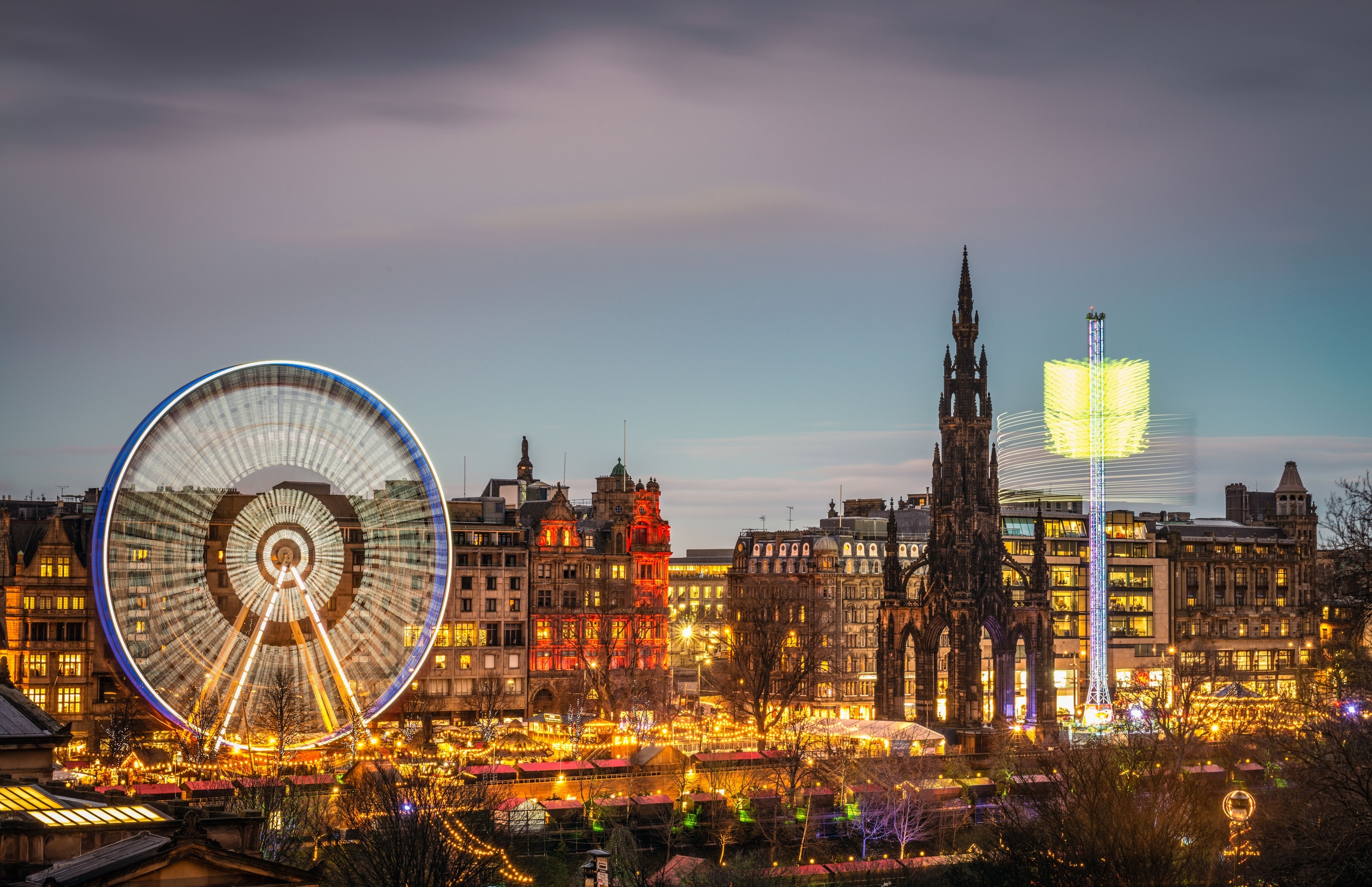evening image of illuminated Christmas market and distant city buildings