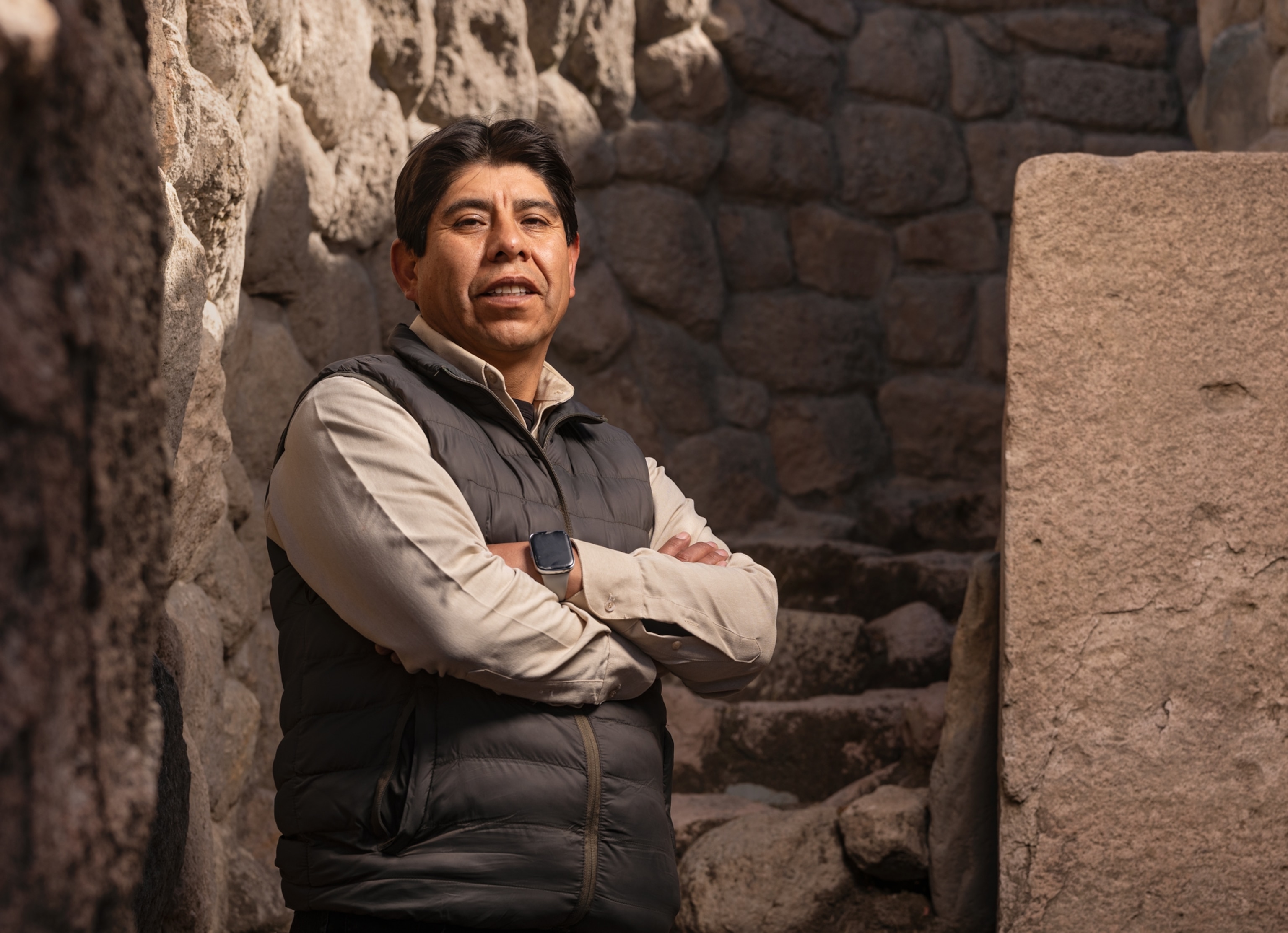 Man with his harms crossed standing by stone staircase and looking into camera.