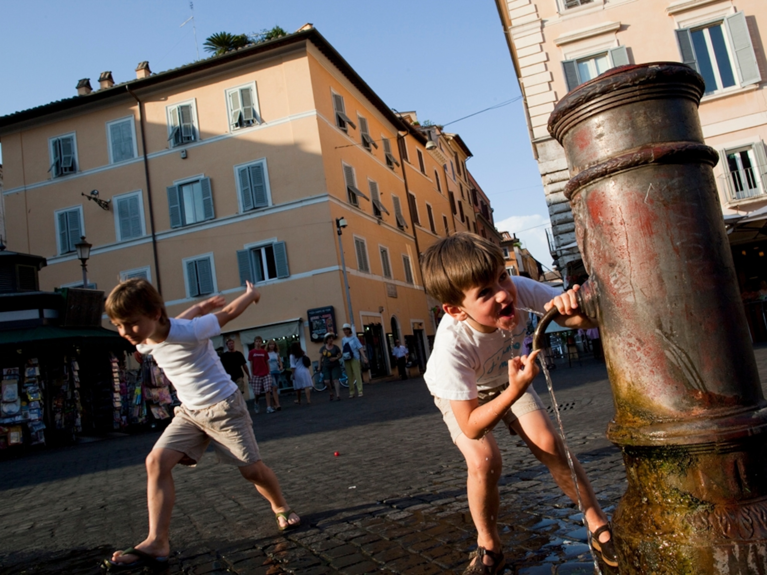 two tourist boys drinking from fountain in Piazza Campo de' Fiori in Rome.