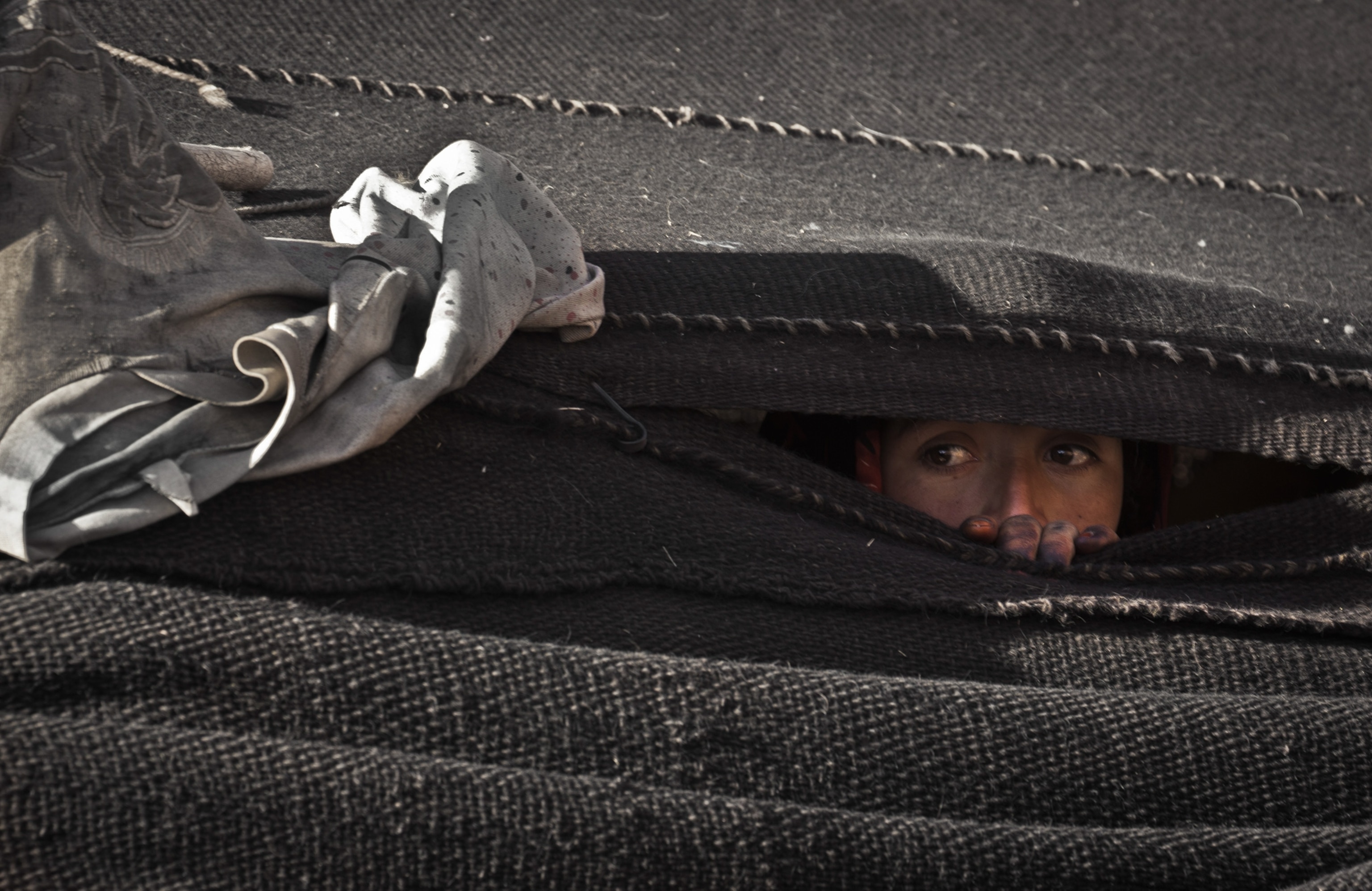 a young girl looking through a gap in a tent