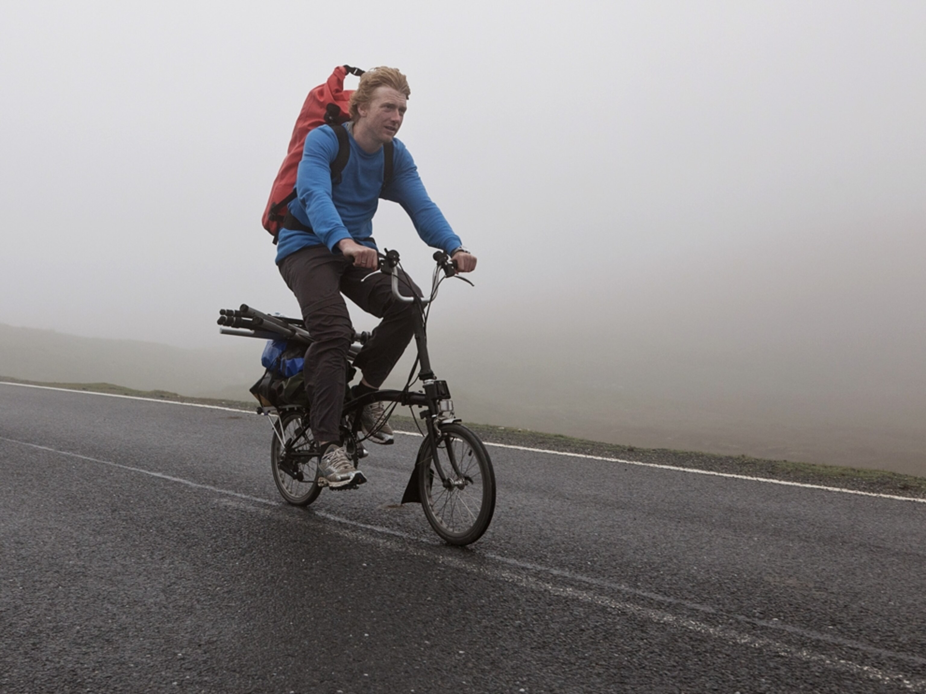 Alastair Humphreys cycling on folding bike in the mist