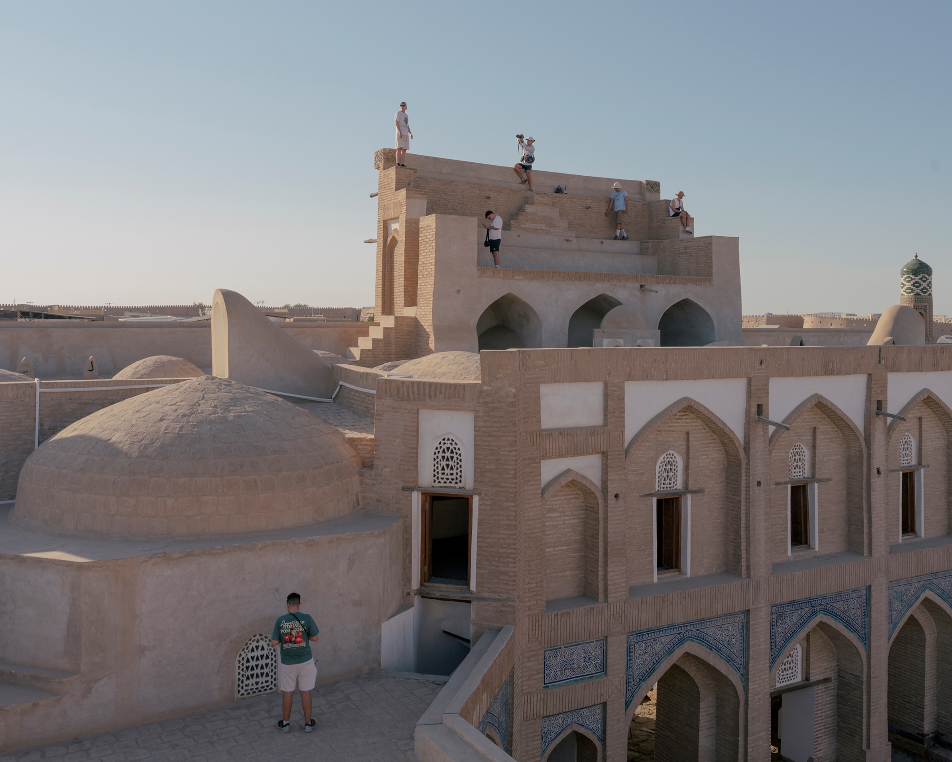 Tourists from Spain photograph each other on Amir Tura Madrasah in Khiva, Uzbekistan, on August 18, 2025.
