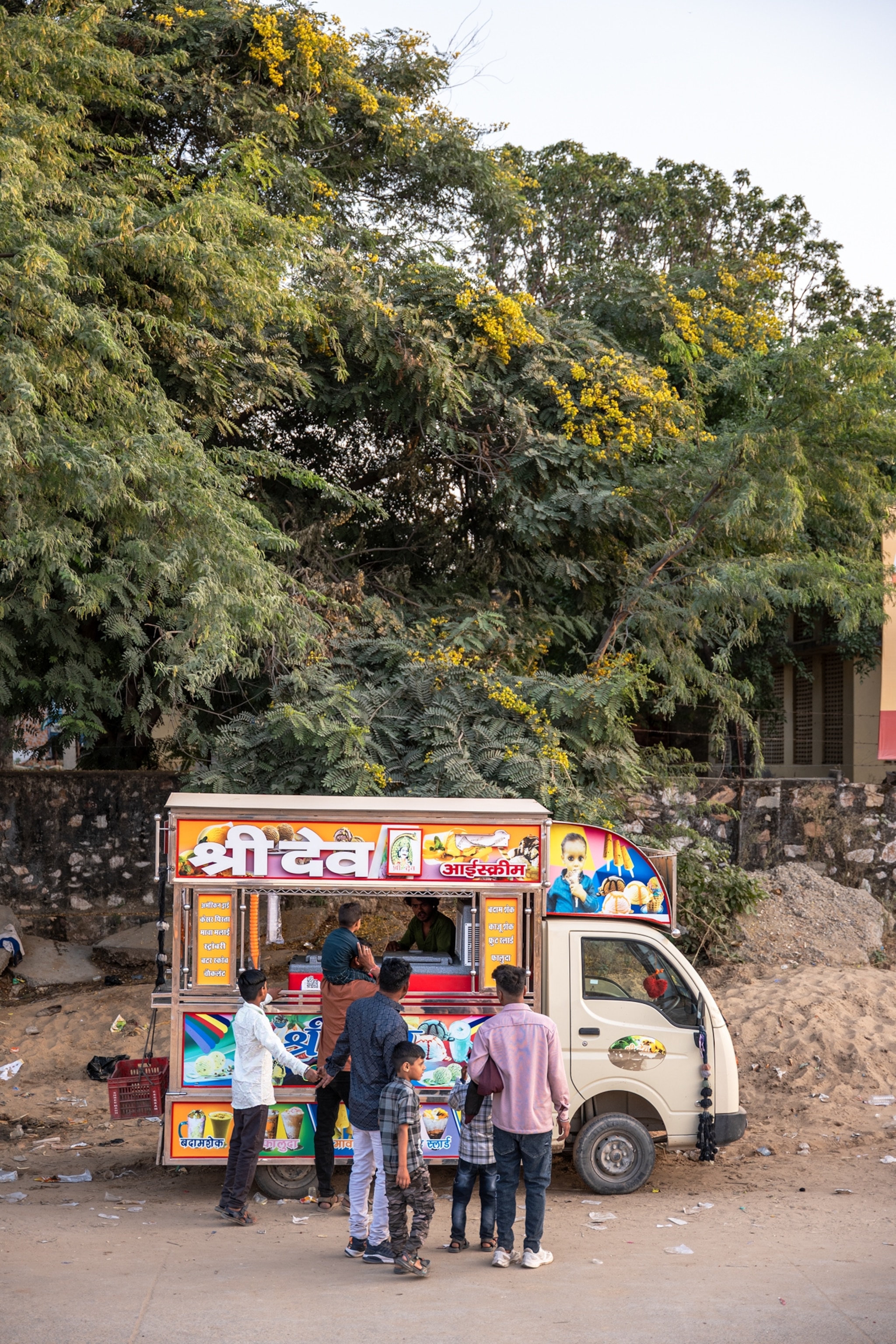 Three men with four boys are getting ice cream from truck.