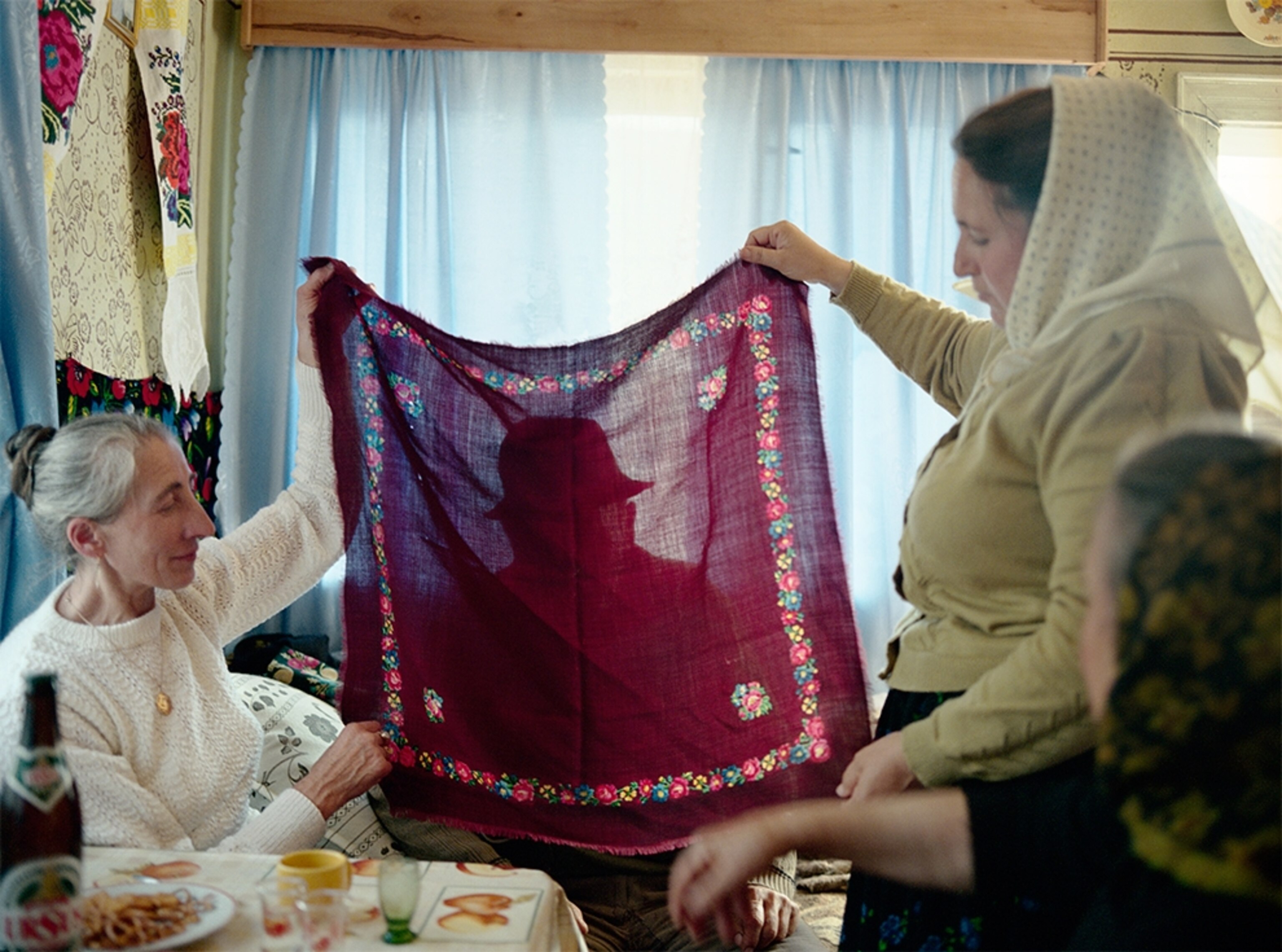 women holding up red headscarf, Maramures, Romania