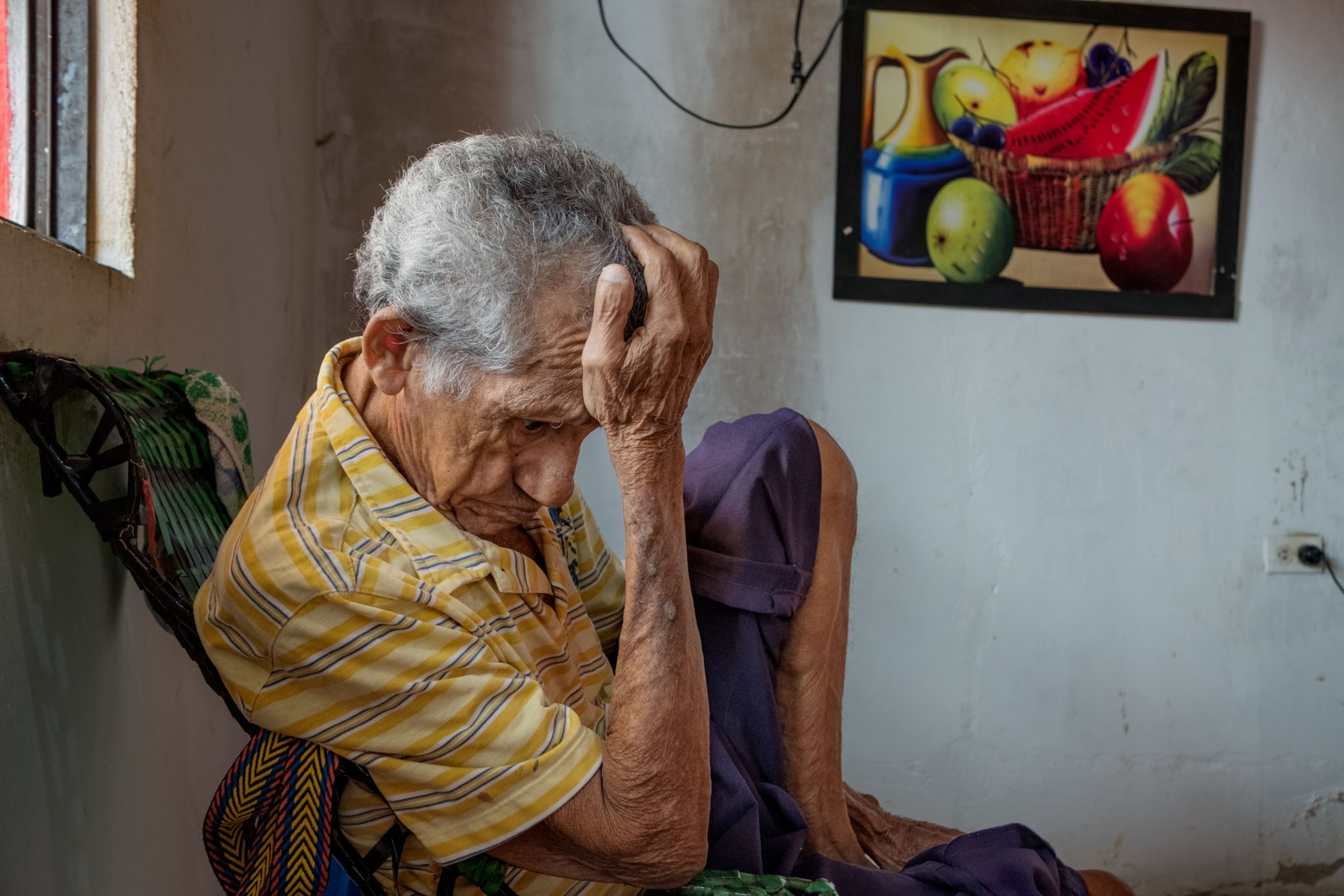 an old man sitting with his hand raised up to his head in a sign on despair