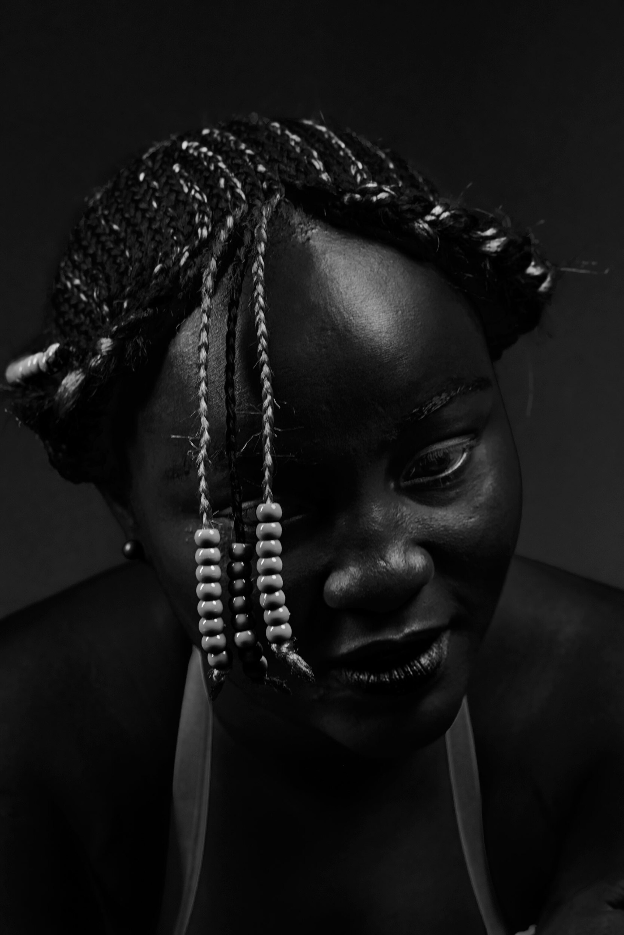 a woman with three braids adorned with beads hanging in front of her face
