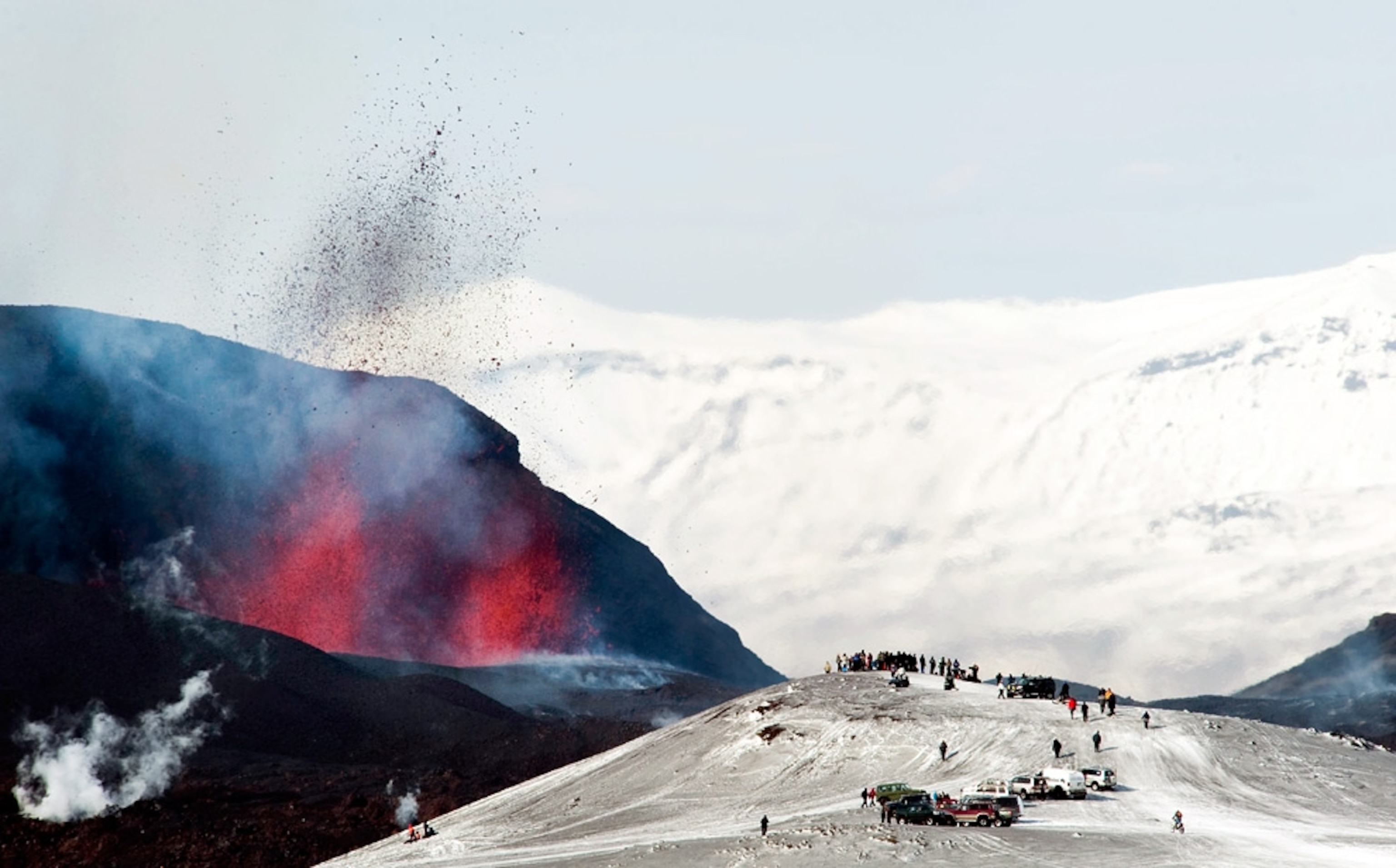 Crowds gather on a snowy hill to watch the eruption of Iceland's Eyjafjallajökull volcano in a picture.